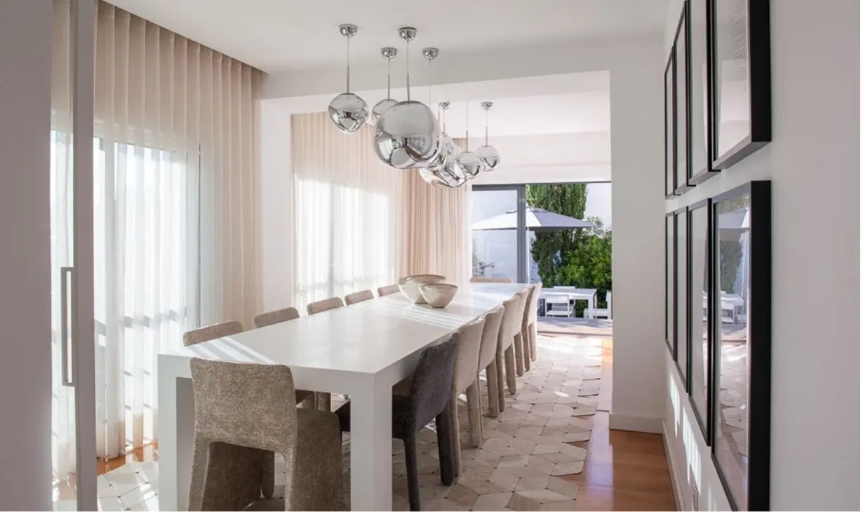 Contemporary dining room in Lisbon with soft natural light, sculptural pendant lighting and a minimalist neutral palette by Atelier Renata Santos Machado.