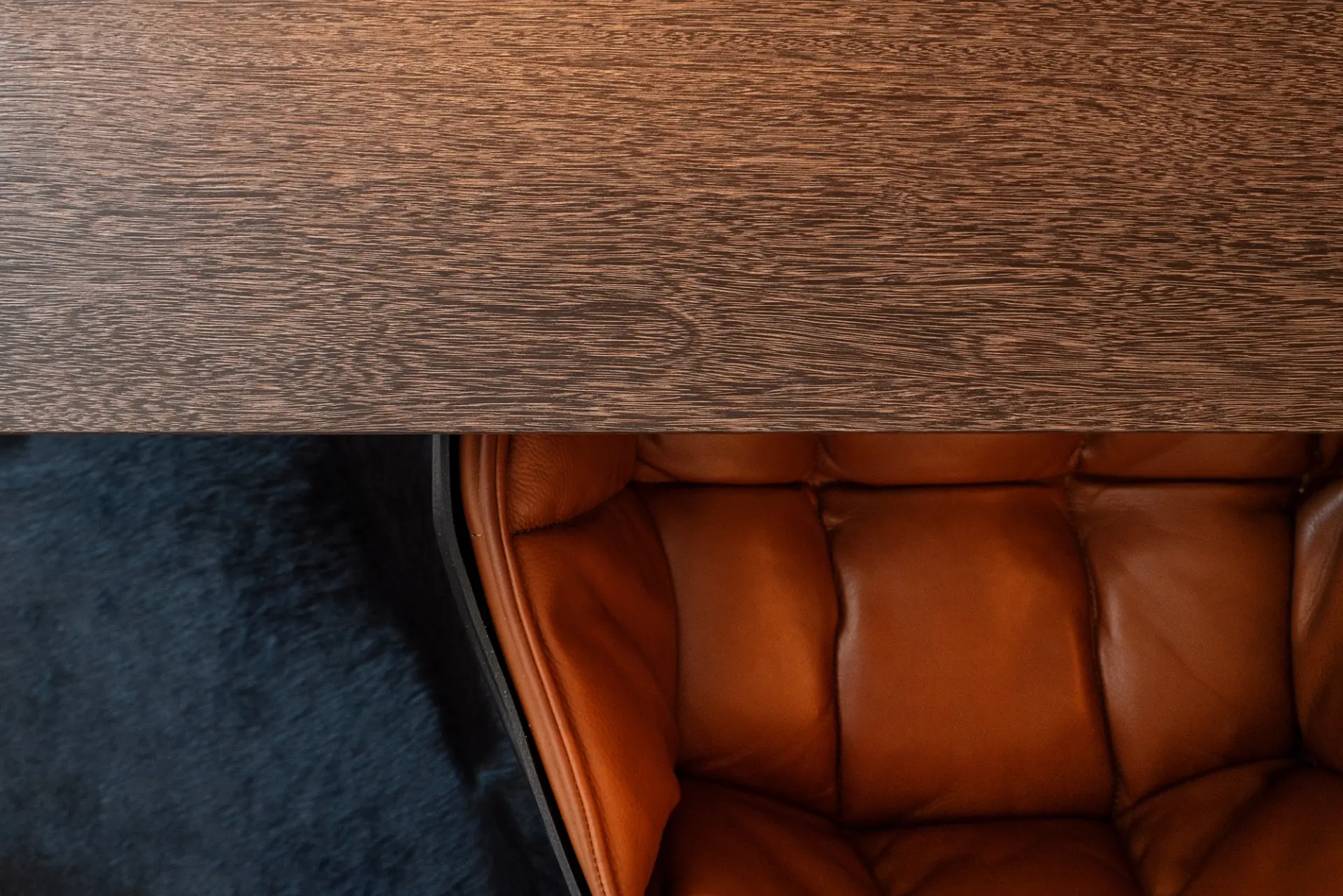 Detalhe de tampo em madeira escura de grão pronunciado e cadeira em couro cognac — design de interiores de luxo, Praça de Espanha, Lisboa, Atelier Renata Santos Machado