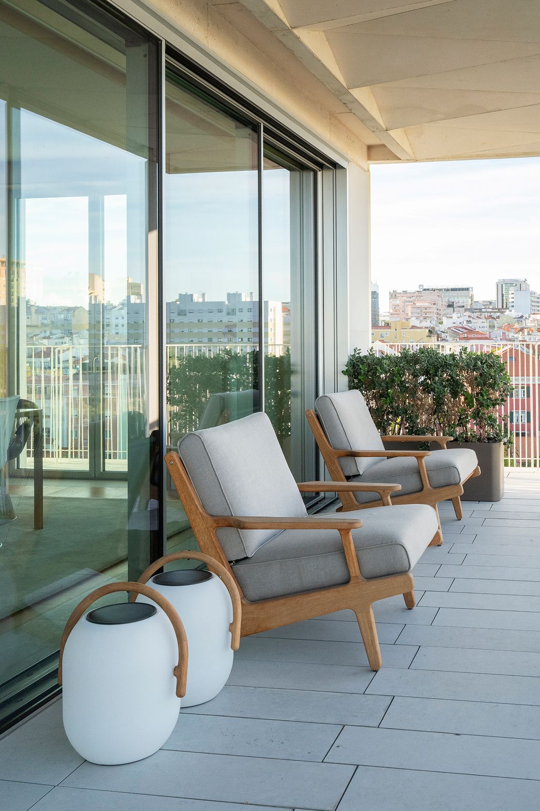 Terraço de penthouse com cadeirões em teca e almofadas cinza sobre vista de Lisboa — design de interiores de luxo, Praça de Espanha, Lisboa, Atelier Renata Santos Machado