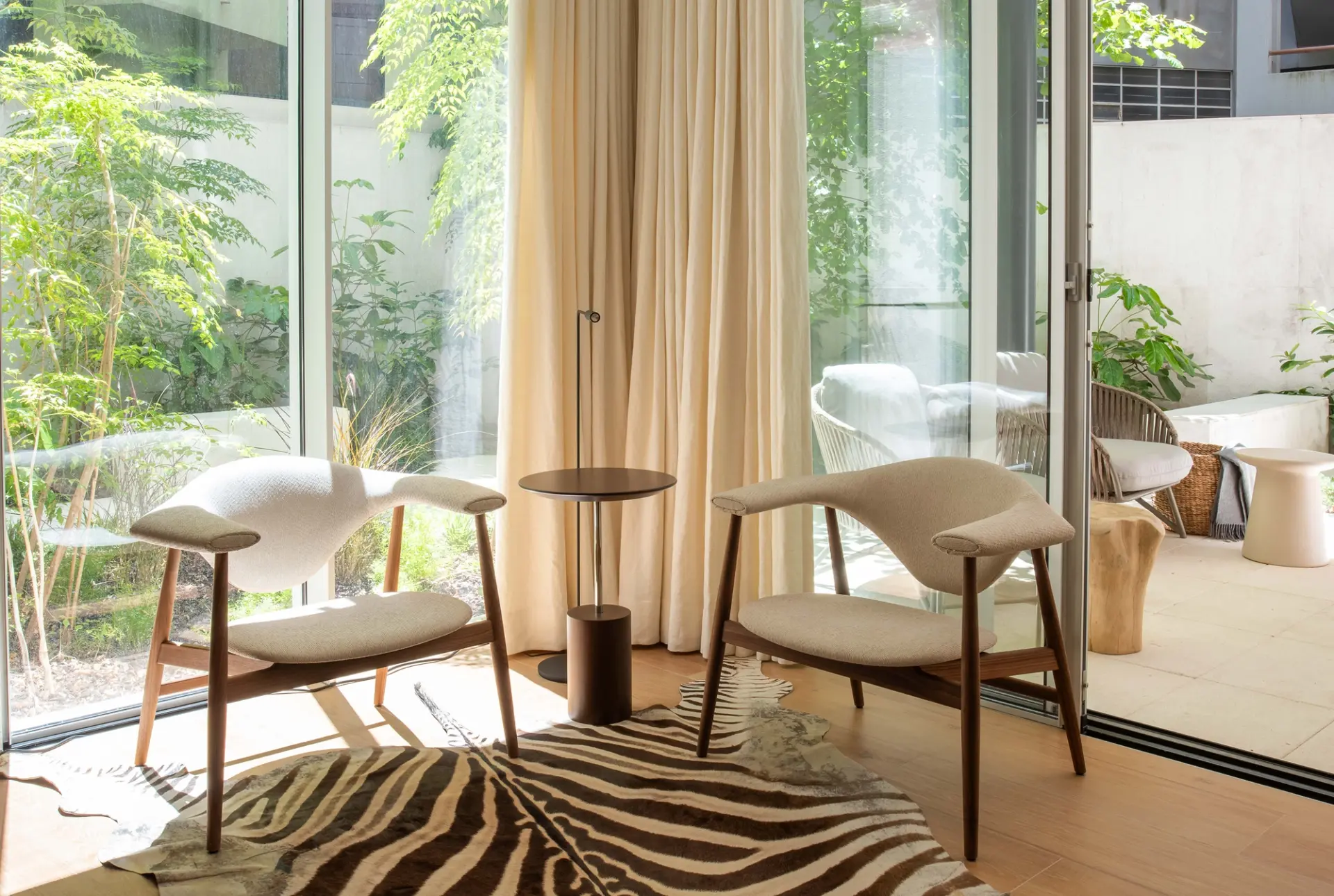 Sala de estar com cadeiras de design, tapete zebra e jardim exterior. Projeto de design de interiores residencial.