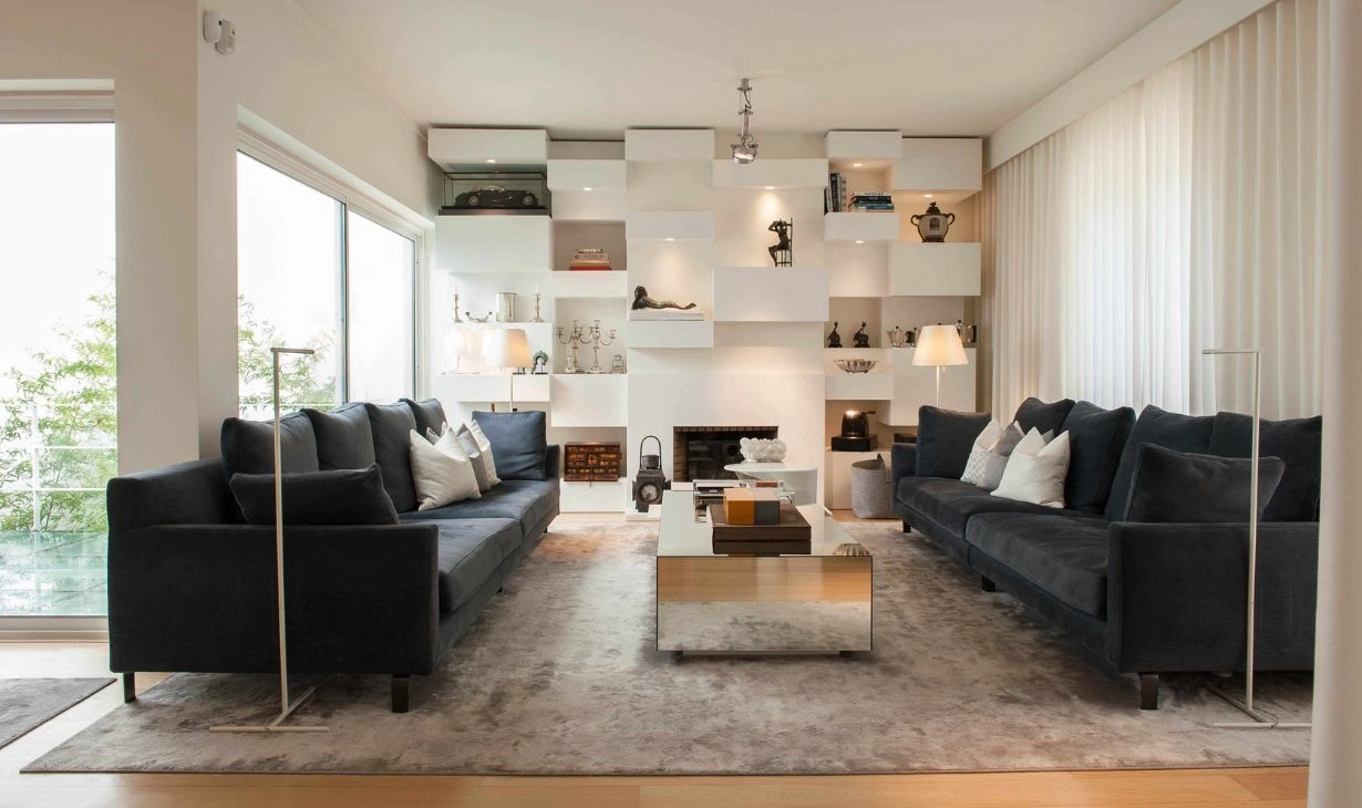 Sala de estar contemporânea em moradia de Sintra, com tons neutros, luz natural abundante, estantes à medida e ambiente elegante e acolhedor.