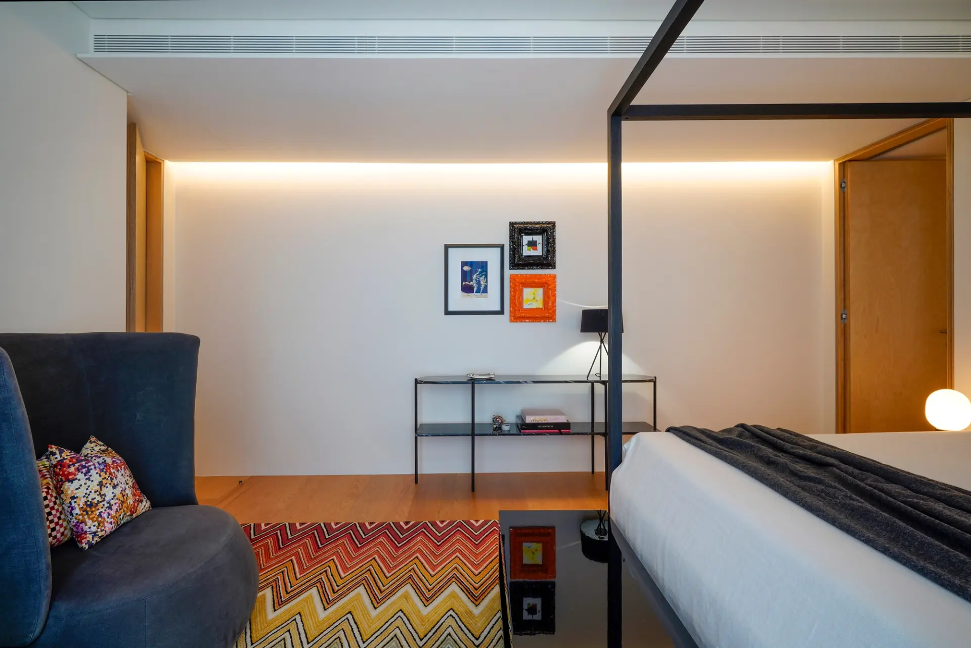 Quarto com poltrona azul-marinho, tapete chevron e cama de dossel em aço preto — design de interiores de luxo, Praça de Espanha, Lisboa, Atelier Renata Santos Machado