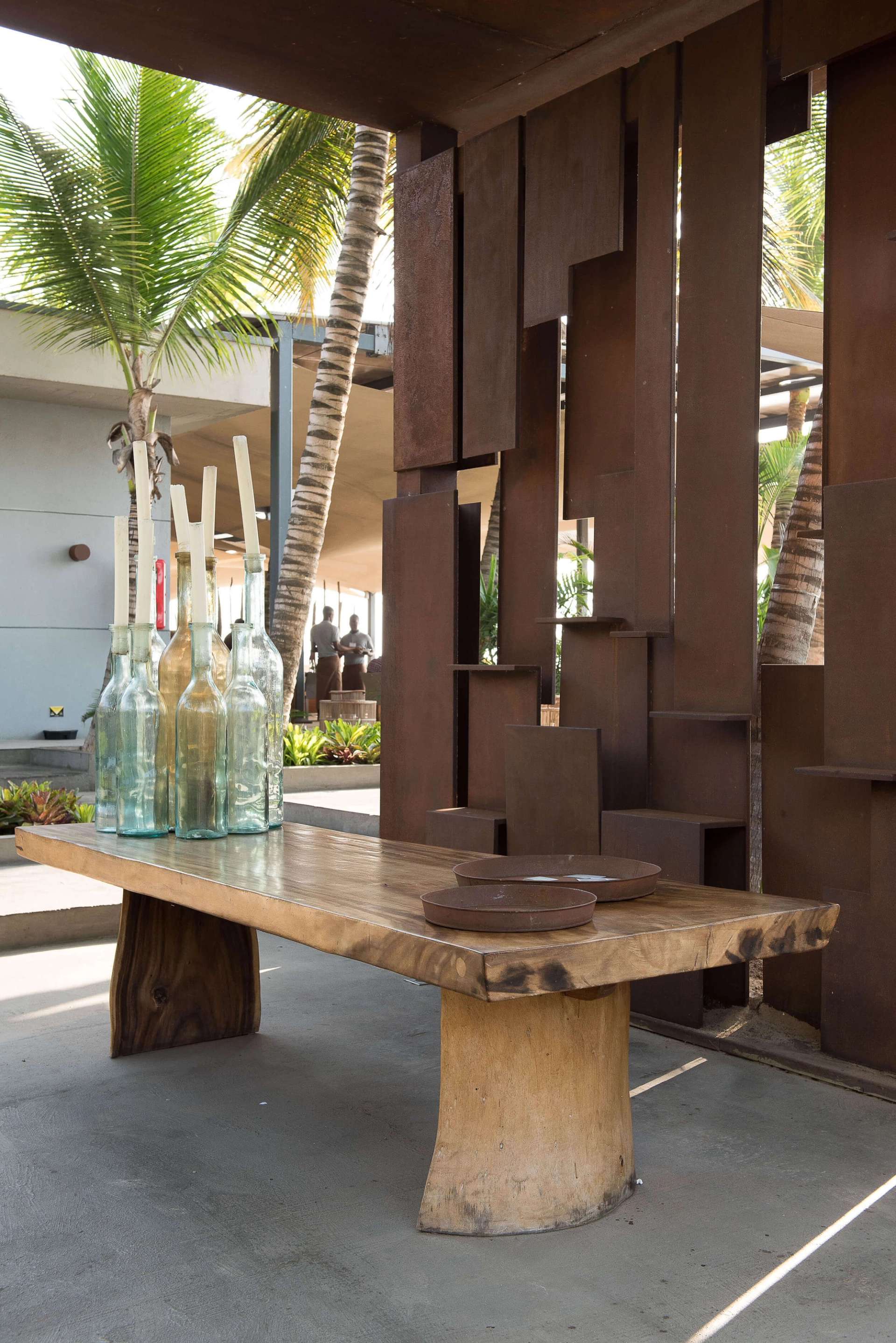 Esplanada com mesa de madeira maciça, garrafas de vidro e biombo metálico — design de interiores de restaurante de luxo Luanda, Angola