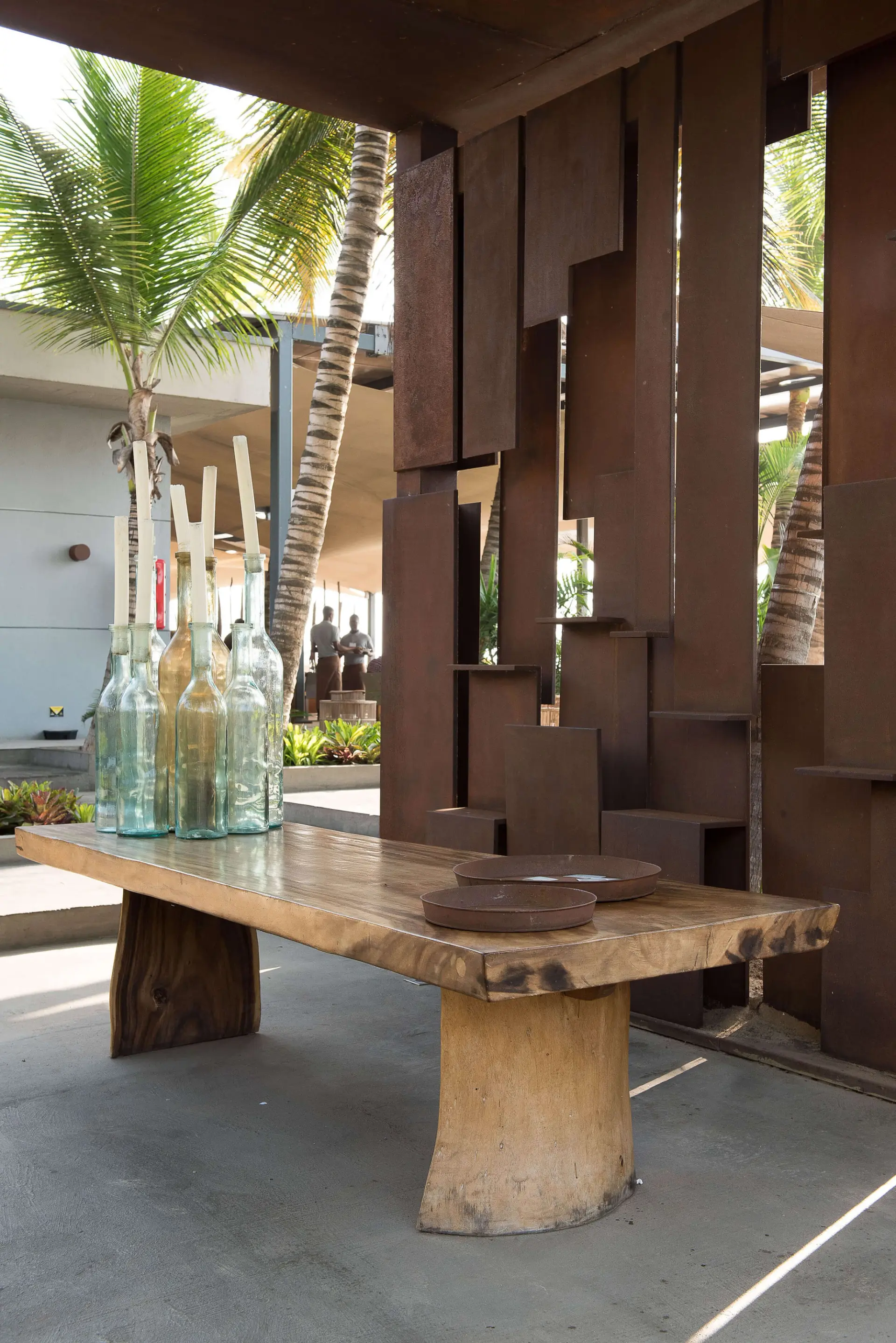 Esplanada com mesa de madeira maciça, garrafas de vidro e biombo metálico — design de interiores de restaurante de luxo Luanda, Angola