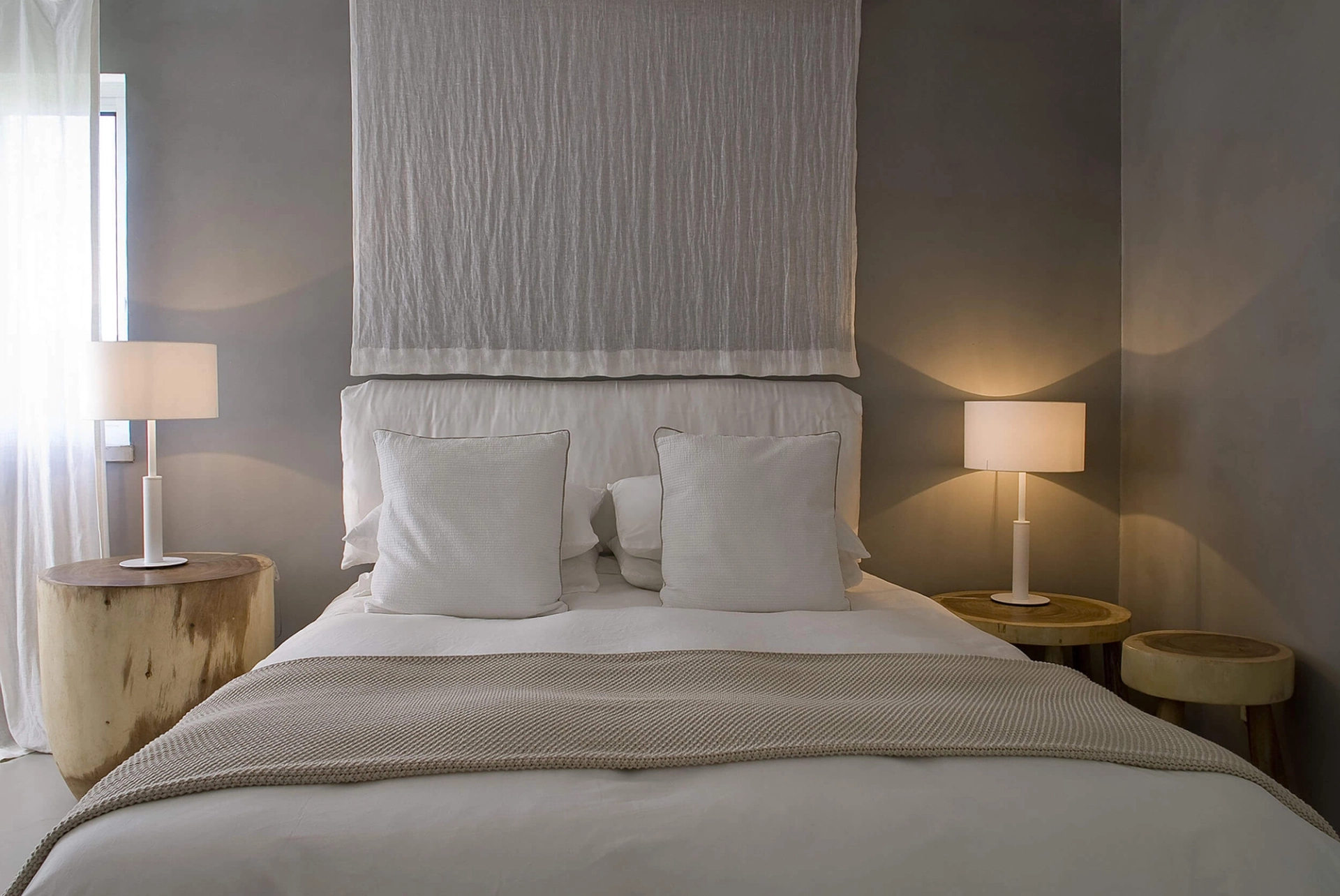 Quarto com painel têxtil drapeado, parede em microcimento e mesas em tronco — design de interiores de luxo Tróia, Setúbal