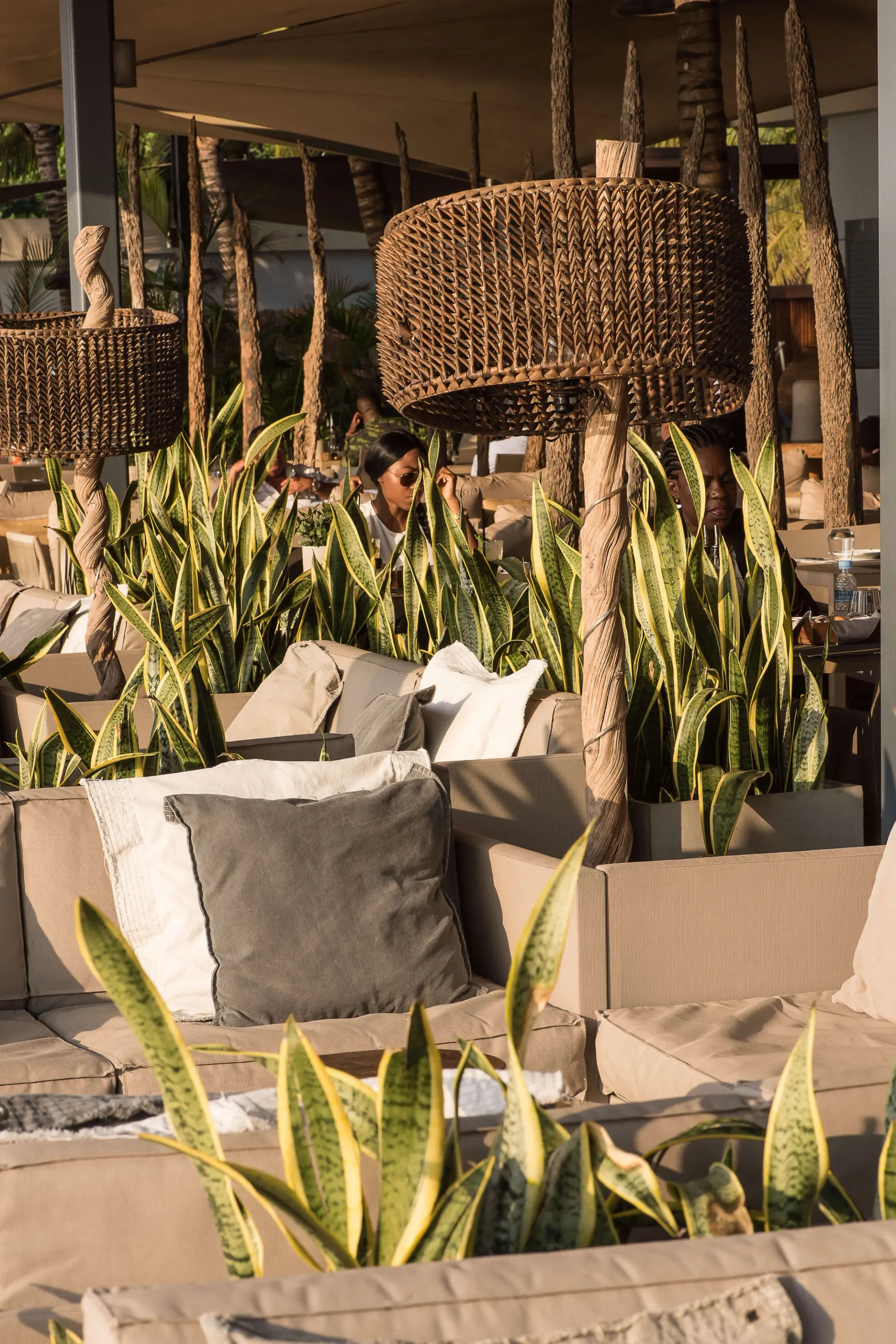 Candeeiros de suspensão em rattan tipo tambor sobre sofás almofadados — design de interiores de restaurante de luxo Luanda, Angola