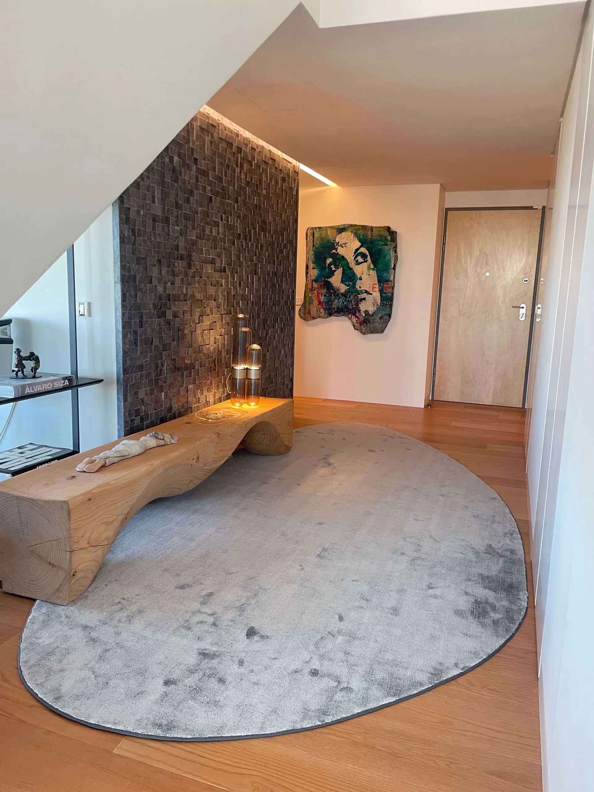 RIVA1920 Mountains solid-timber bench, stacked split-face stone wall and a colourful portrait artwork — luxury entrance hall