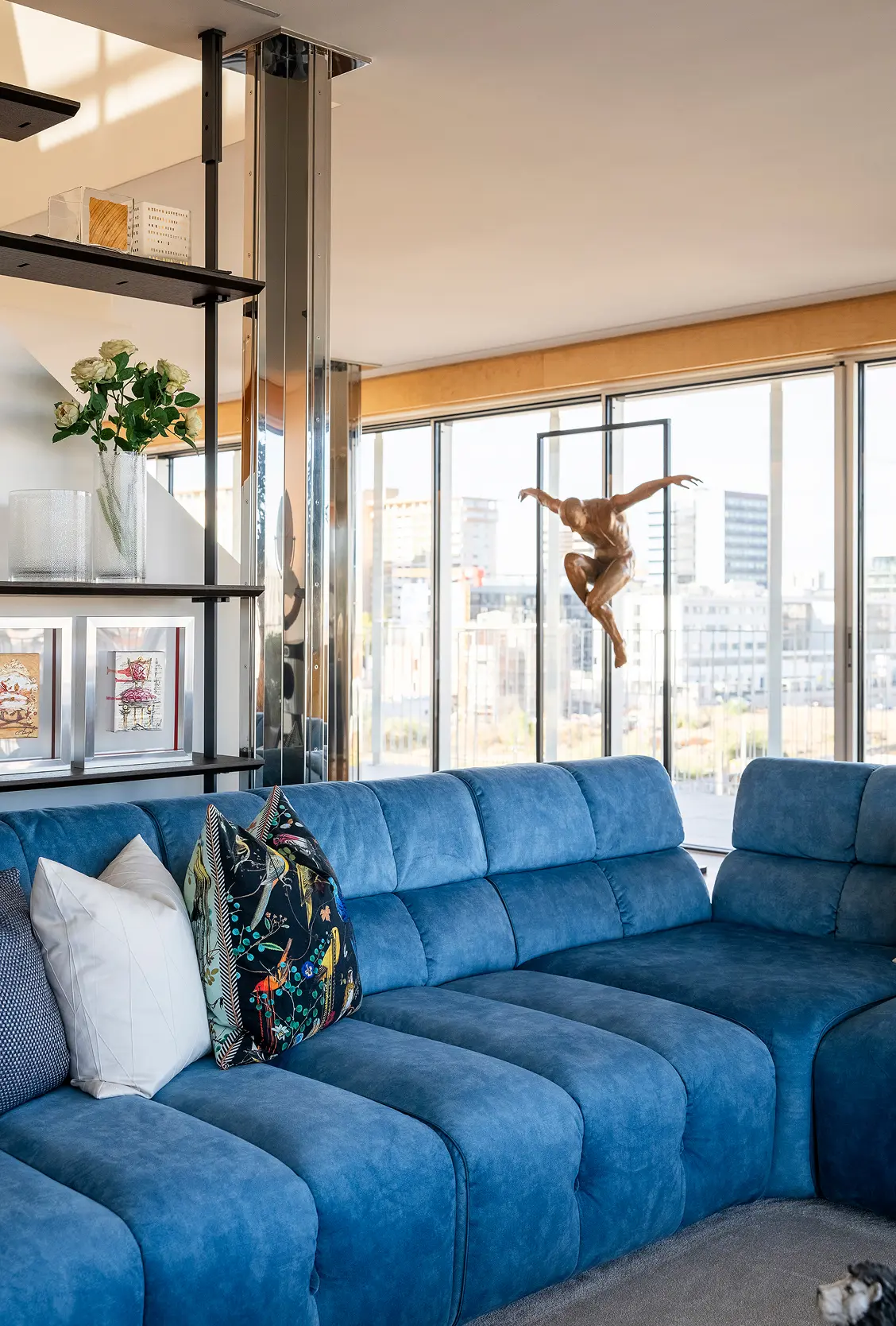 Detalhe de sala de estar de penthouse com sofá em veludo azul, escultura figurativa e estante industrial — design de interiores de luxo na Praça de Espanha, Lisboa, Atelier Renata Santos Machado