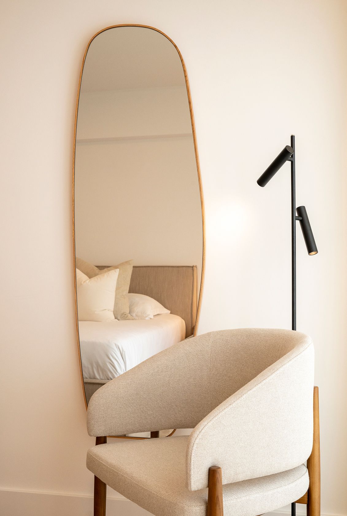 Organic wood-framed mirror, black articulated reading floor lamp and cream bouclé armchair — luxury décor details