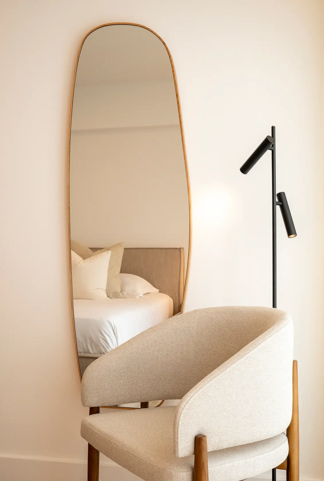 Organic wood-framed mirror, black articulated reading floor lamp and cream bouclé armchair — luxury décor details