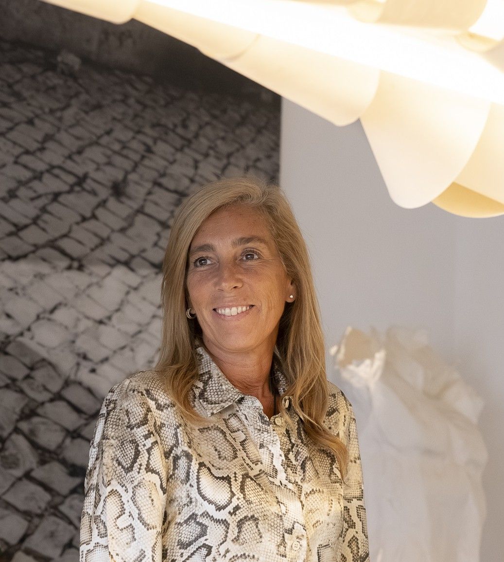 Renata Santos Machado, fundadora do atelier, a sorrir, com uma fotografia de calçada portuguesa ao fundo