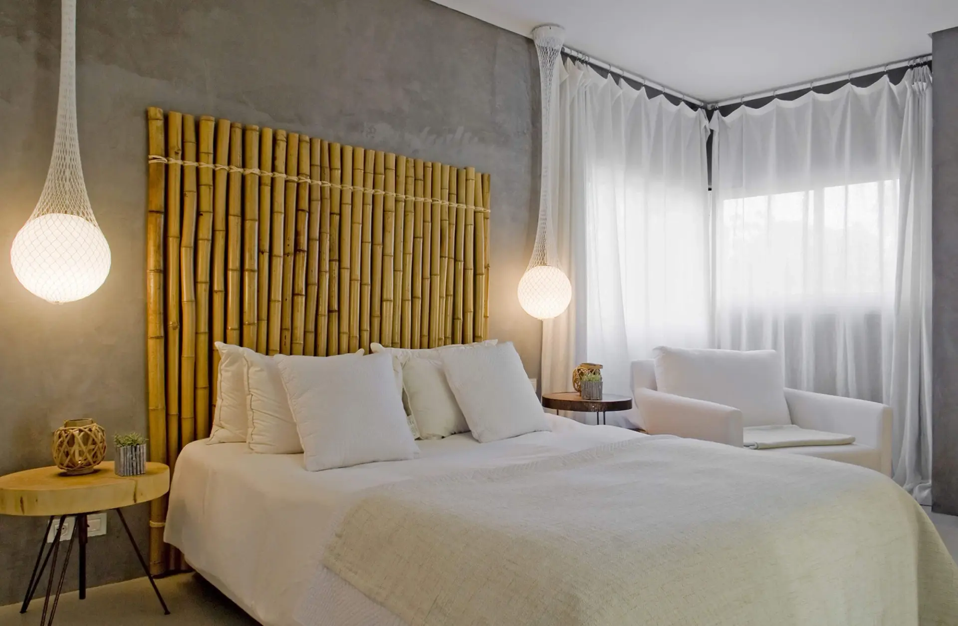 Quarto com cabeceira em bambu natural, parede em microcimento e candeeiros em rede — design de interiores de luxo Tróia, Setúbal