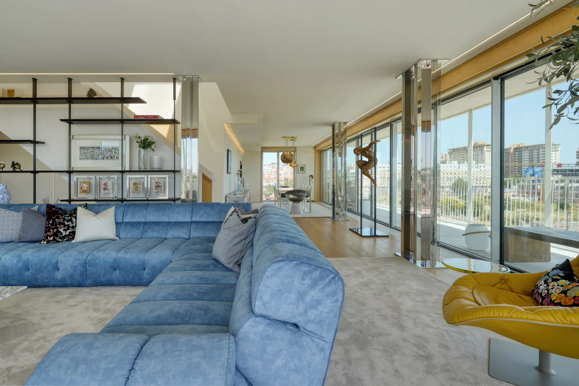 Sala de estar de penthouse com sofá modular em veludo azul, poltrona em mostarda e estante industrial com vista sobre Lisboa — design de interiores de luxo na Praça de Espanha, Lisboa, Atelier Renata Santos Machado