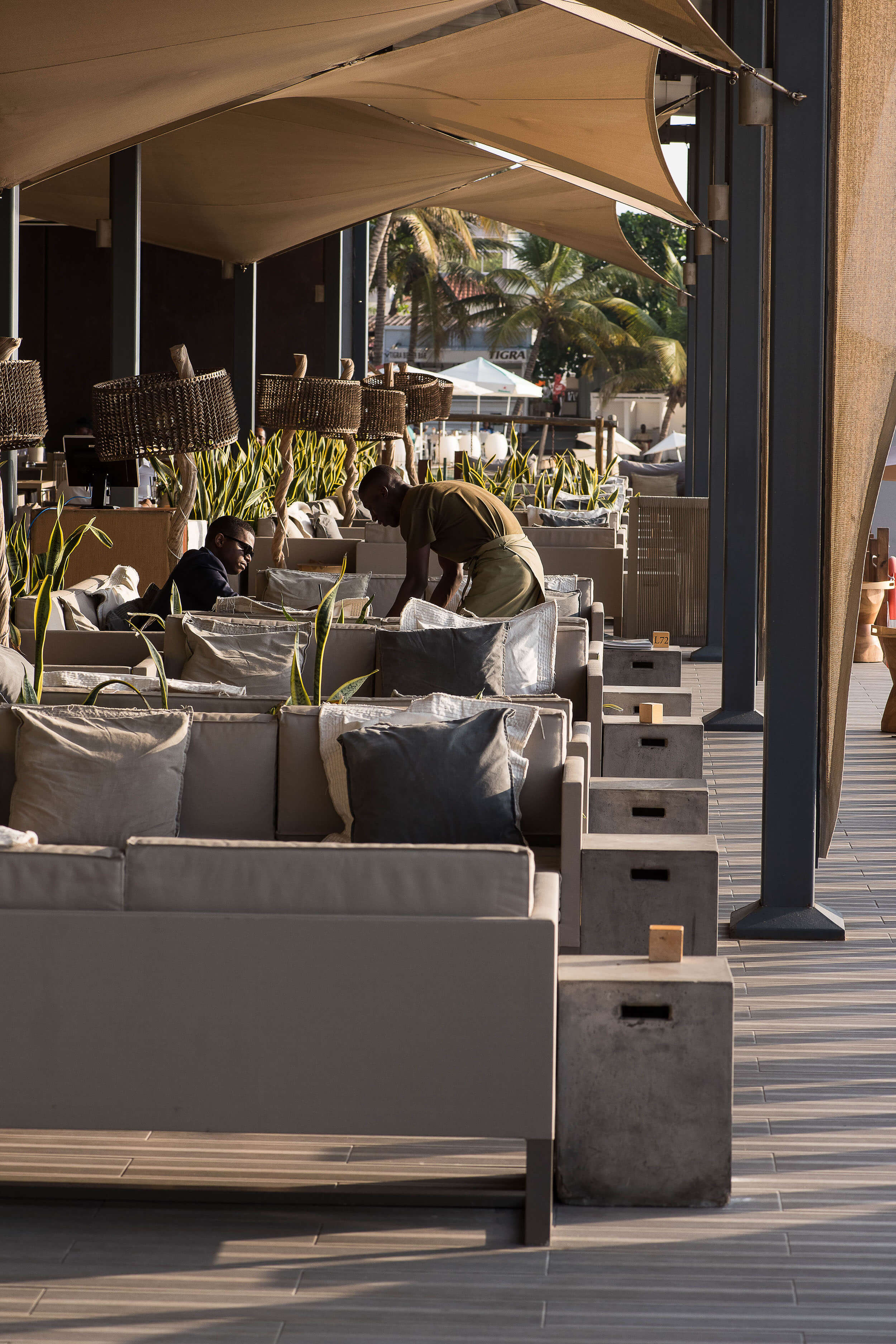 Lounge coberto com candeeiros de suspensão em rattan e mesas em betão — design de interiores de restaurante de luxo Luanda, Angola