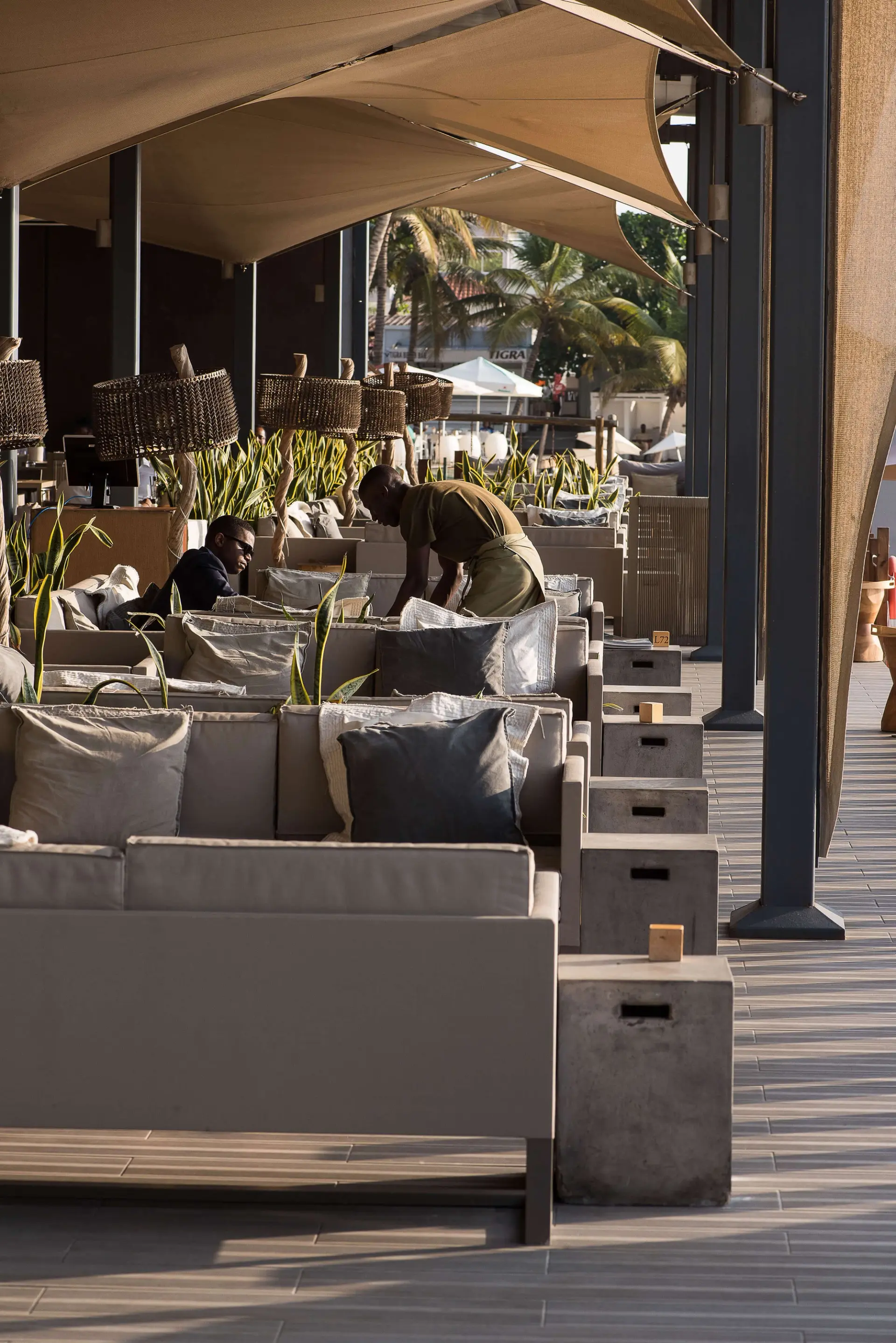 Lounge coberto com candeeiros de suspensão em rattan e mesas em betão — design de interiores de restaurante de luxo Luanda, Angola