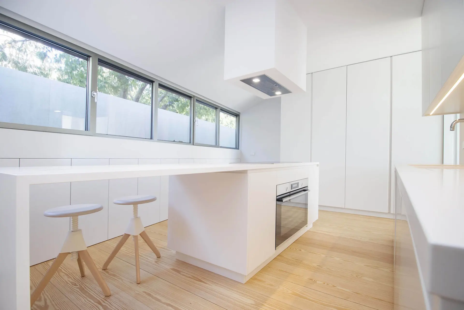 Cozinha em branco total com ilha de refeição, bancos MAGIS Jerry e janela horizontal corrida — design de interiores de luxo, Lisboa, Atelier Renata Santos Machado