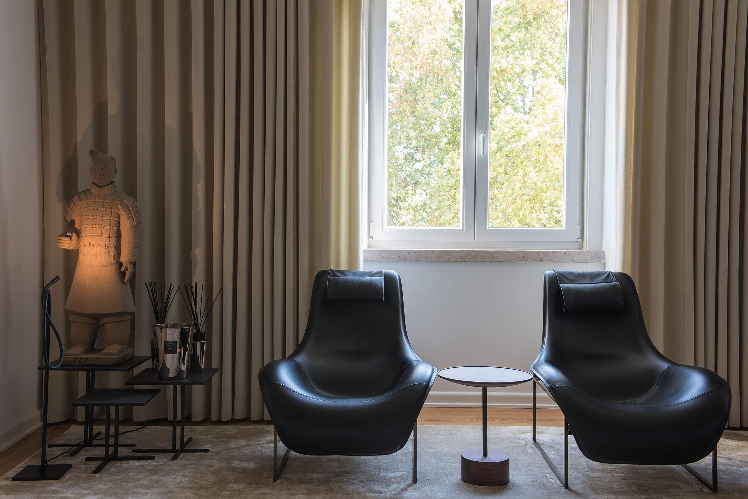 Zona de leitura com cadeirões B&B Italia em couro preto e escultura de soldado em terracota — design de interiores de luxo, Avenidas Novas, Atelier Renata Santos Machado