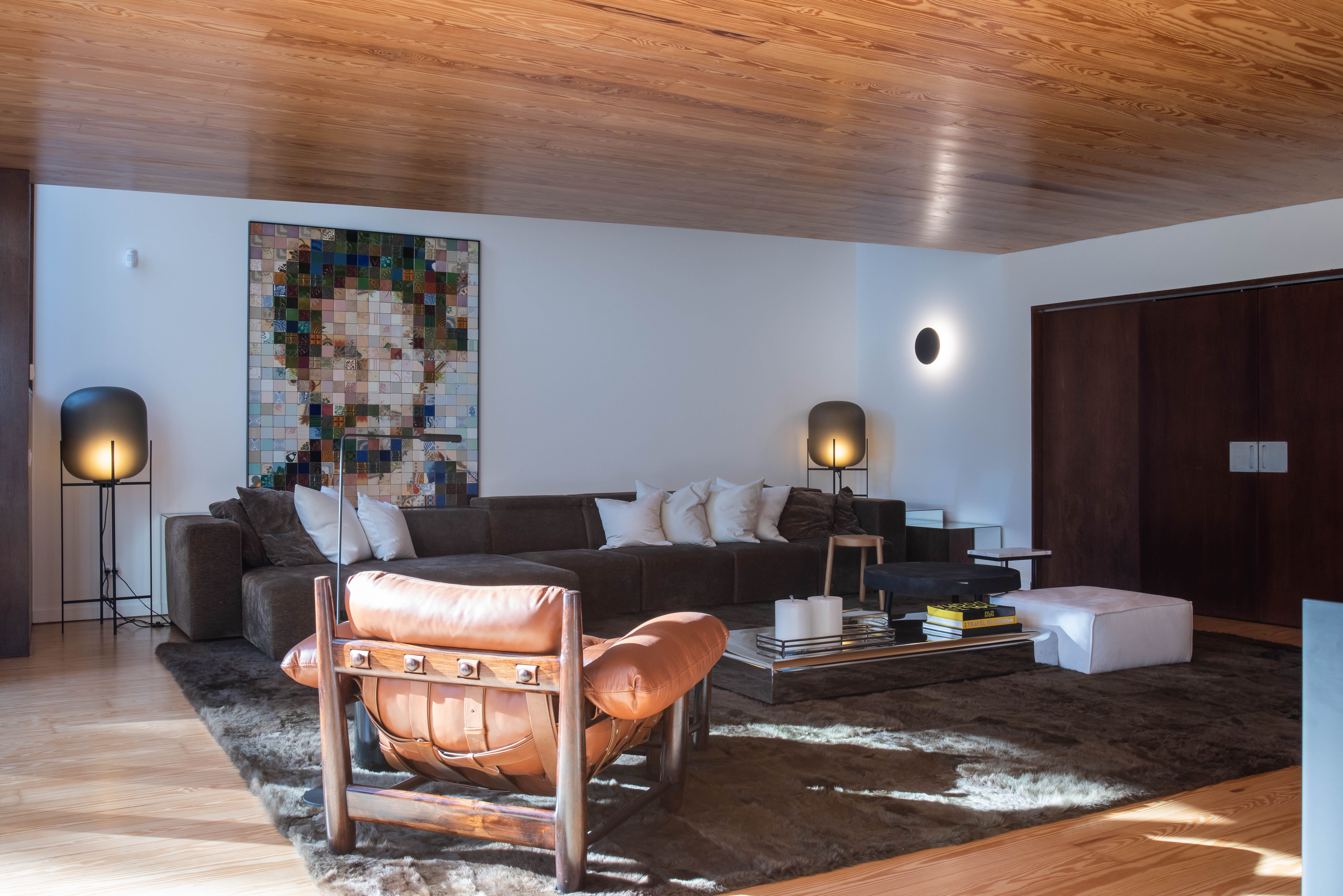 Sala de estar de projeto de design de interiores com sofá, cadeirão em couro e peças de arte