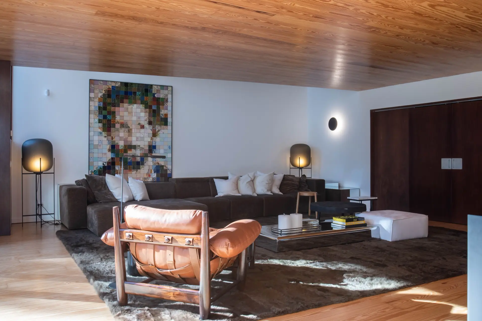 Sala de estar de projeto de design de interiores com sofá, cadeirão em couro e peças de arte