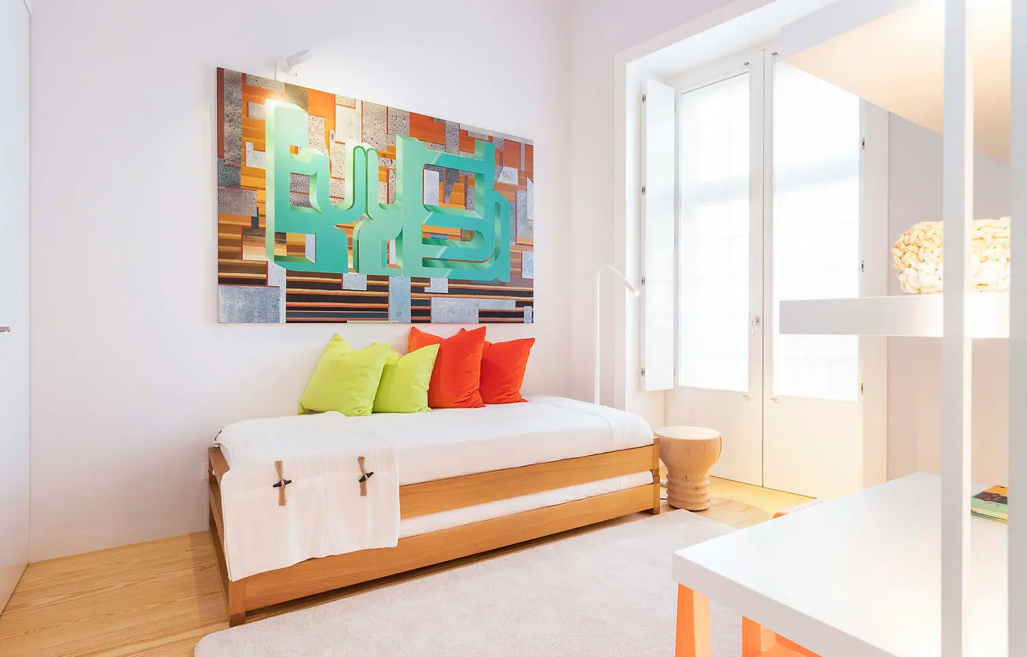 Youth bedroom with a wooden sofa bed, colorful cushions, and modern abstract art in vibrant tones.