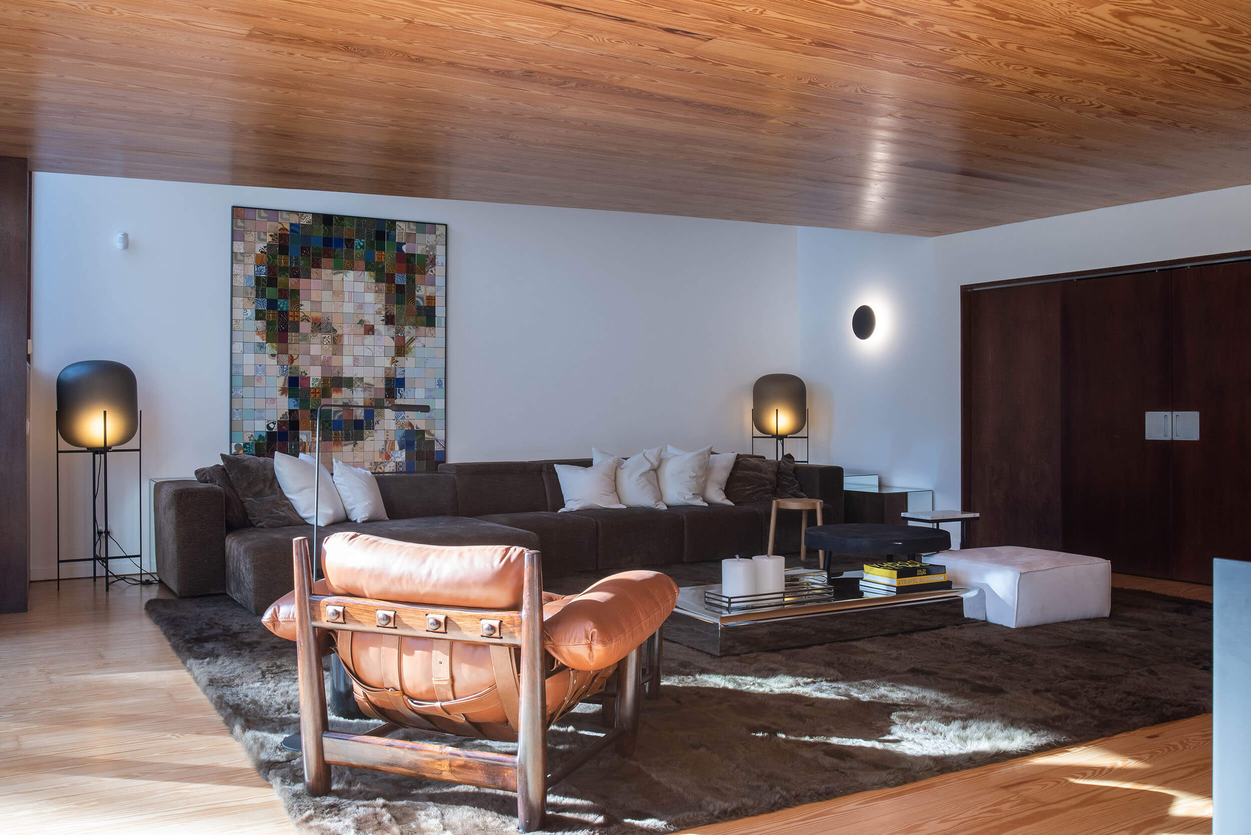 Sala de estar com design de interiores moderno, totalmente mobilada com sofá, poltrona, iluminação e decoração.