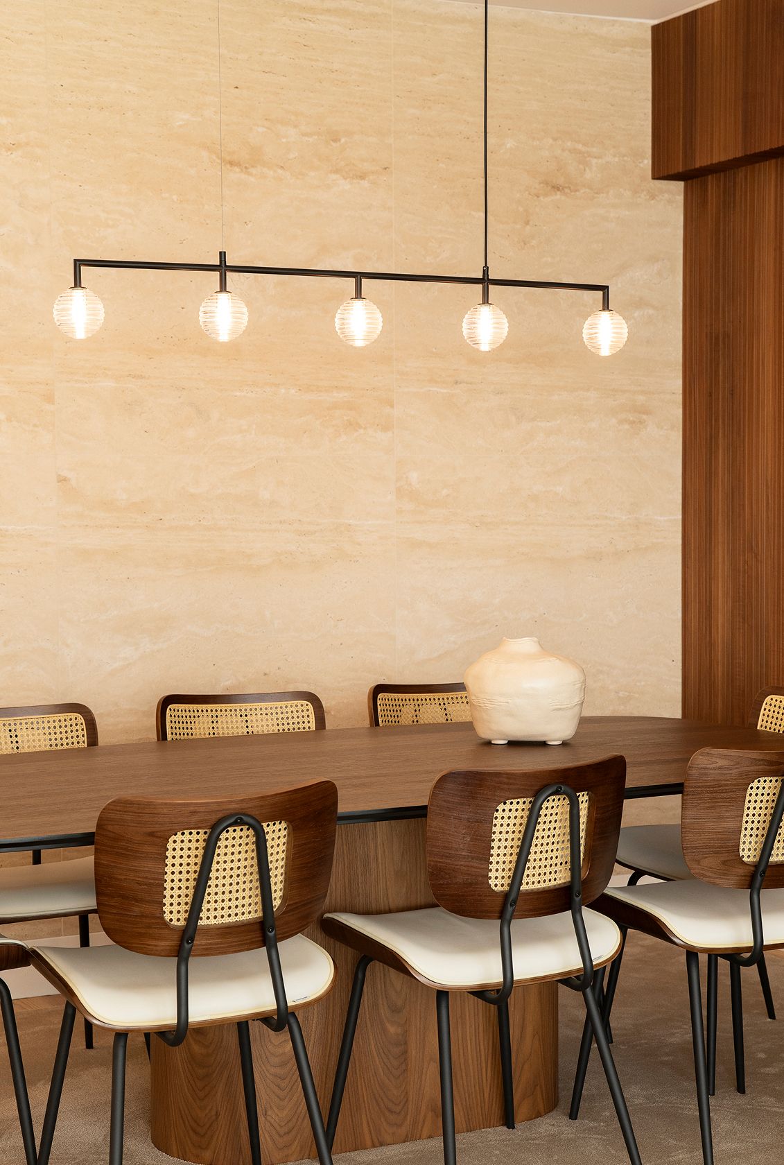 Walnut-and-cane dining chairs, sculptural wood pedestal table and glass-globe suspension — luxury décor details