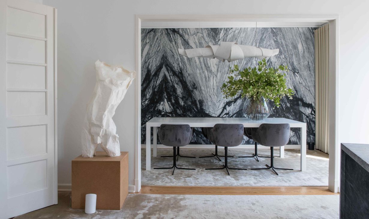 Contemporary dining room interior design project in Lisbon by Atelier Renata Santos Machado, featuring a marble statement wall, sculptural lighting and neutral furnishings.