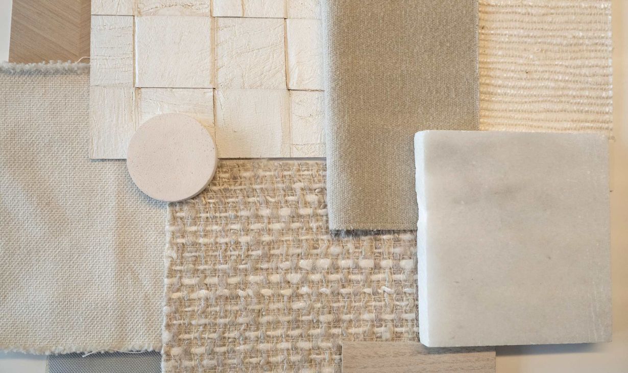 Interior design material selection process in Portugal by Atelier Renata Santos Machado, featuring fabric samples, textured finishes and natural stone.