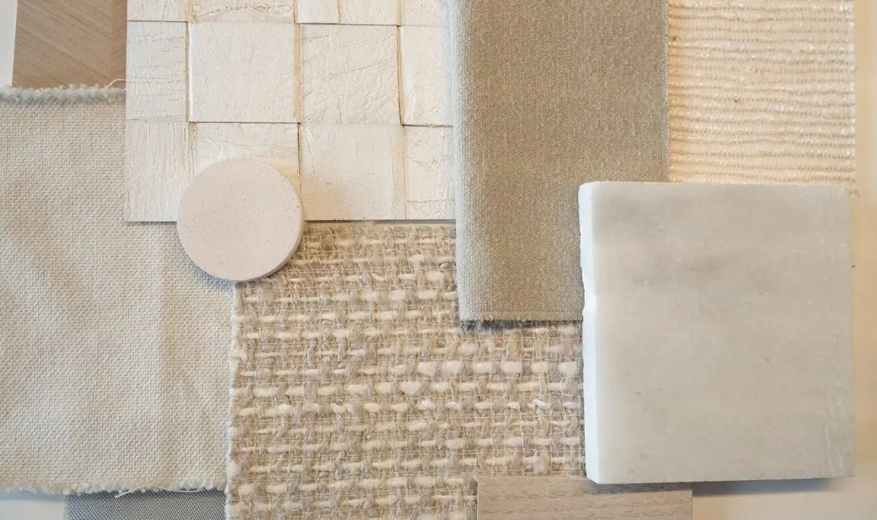 Interior design material selection process in Portugal by Atelier Renata Santos Machado, featuring fabric samples, textured finishes and natural stone.