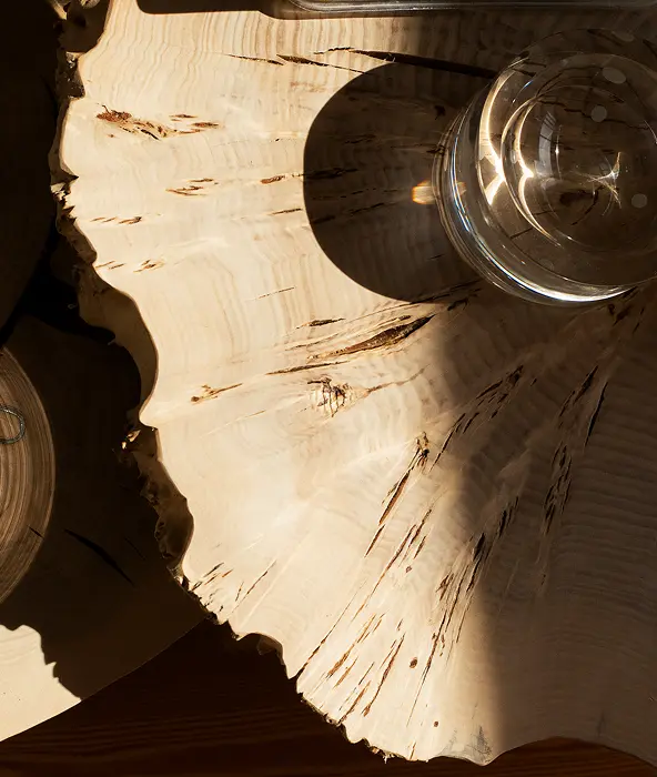 Detail of natural wood cross-section table with glass vessel — noble material curation in luxury interior design project by Atelier Renata Santos Machado, Lisbon