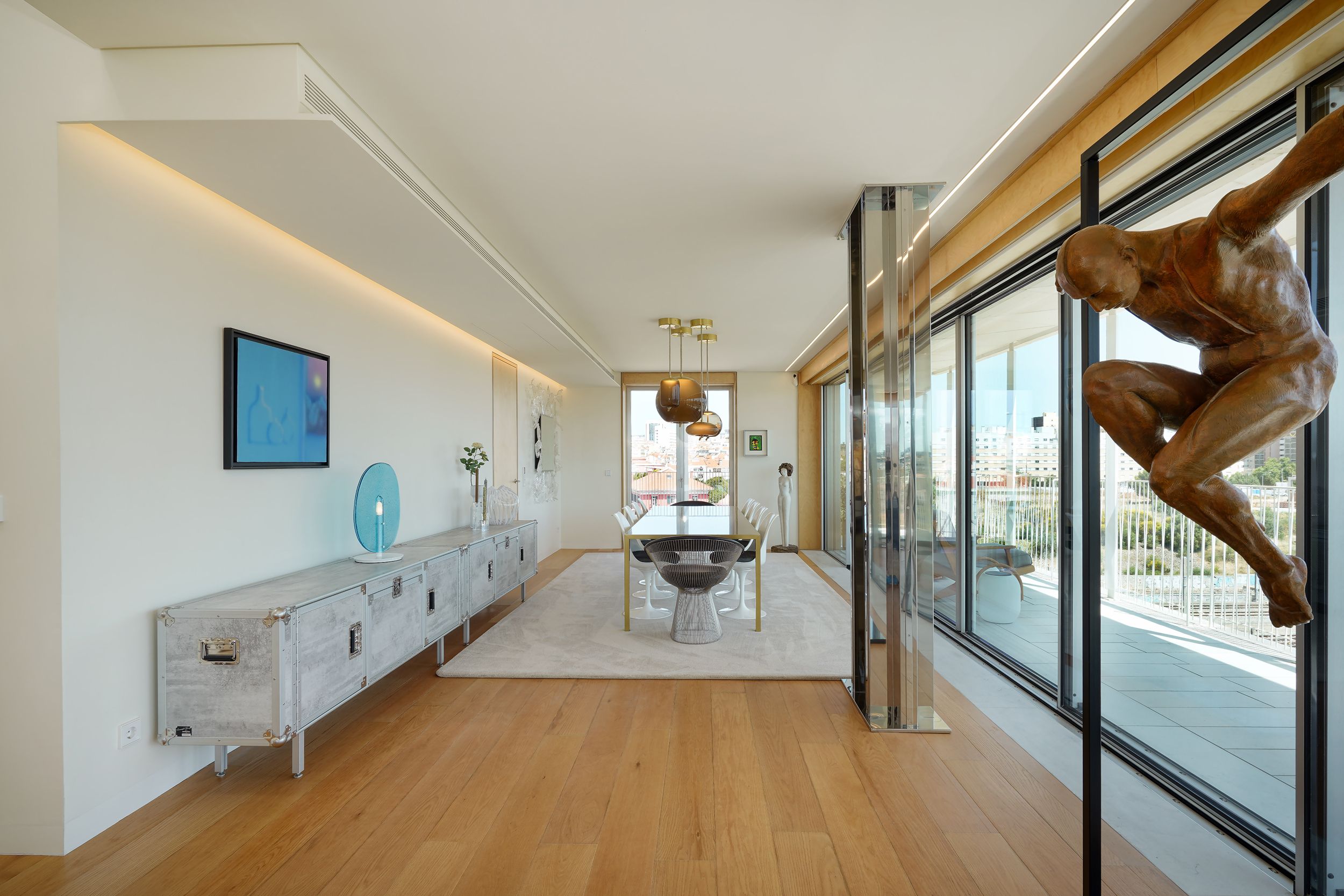 Sala de jantar de penthouse com aparador metálico em comprimento total, escultura em bronze e perspectiva para terraço com vista — design de interiores de luxo na Praça de Espanha, Lisboa, Atelier Renata Santos Machado