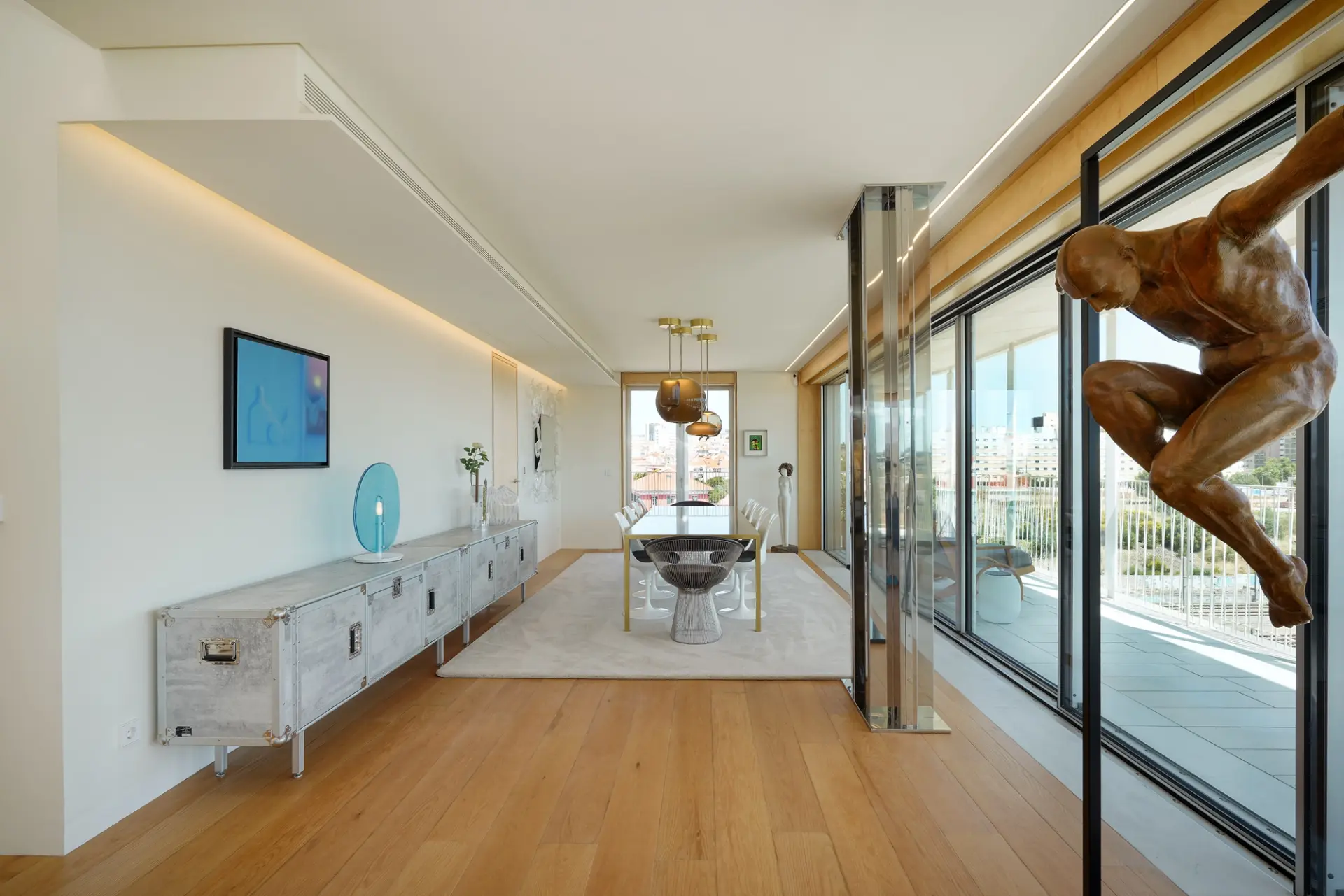 Sala de jantar de penthouse com aparador metálico em comprimento total, escultura em bronze e perspectiva para terraço com vista — design de interiores de luxo na Praça de Espanha, Lisboa, Atelier Renata Santos Machado