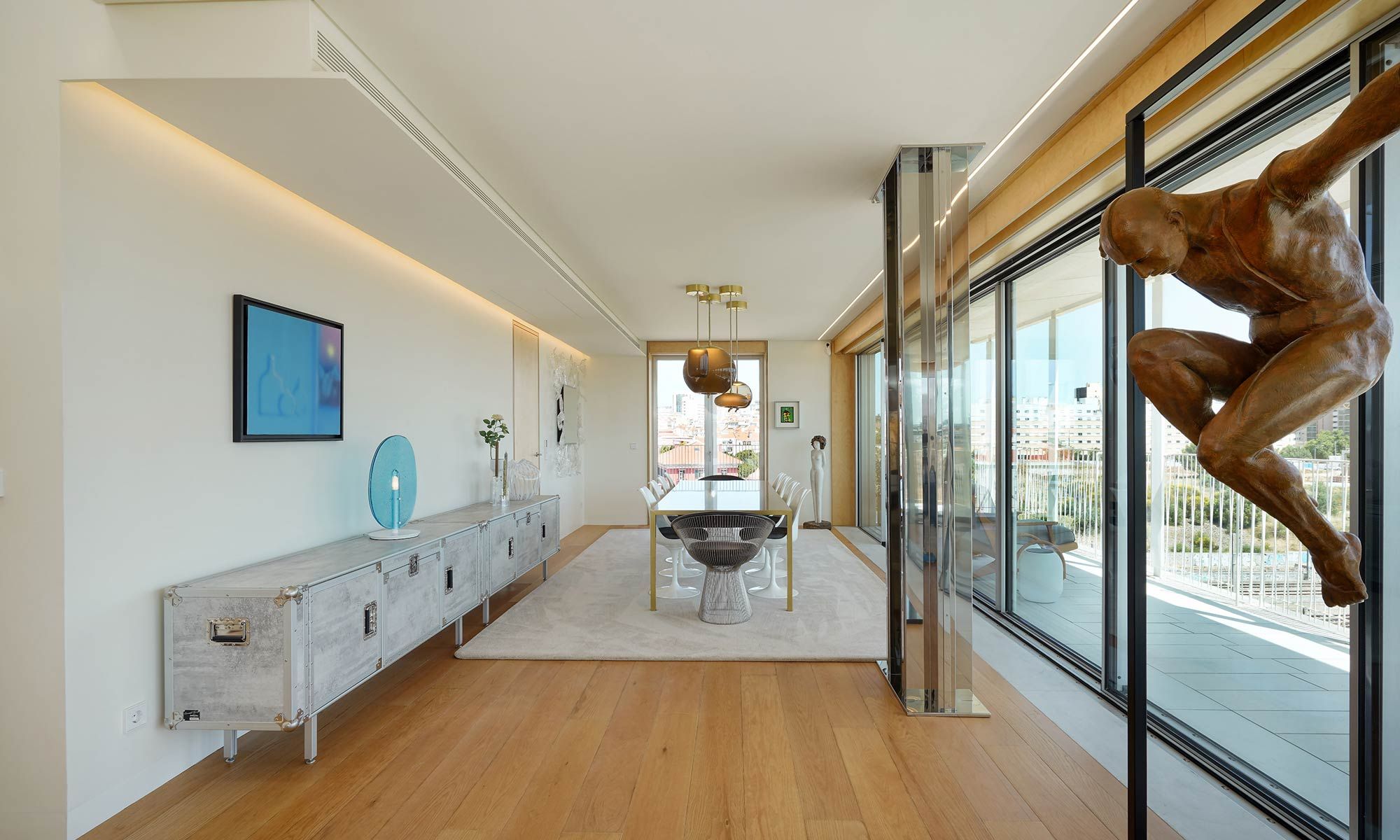 Corredor e sala de jantar com escultura em bronze, aparador metálico e vista sobre terraço — design de interiores de luxo em Lisboa, Atelier Renata Santos Machado