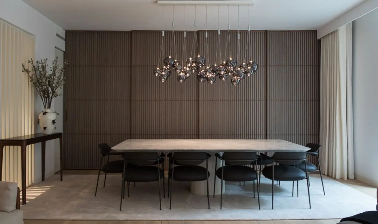 Luxury dining room interior design project in Portugal by Atelier Renata Santos Machado, featuring wood panelled walls, marble table and statement lighting.