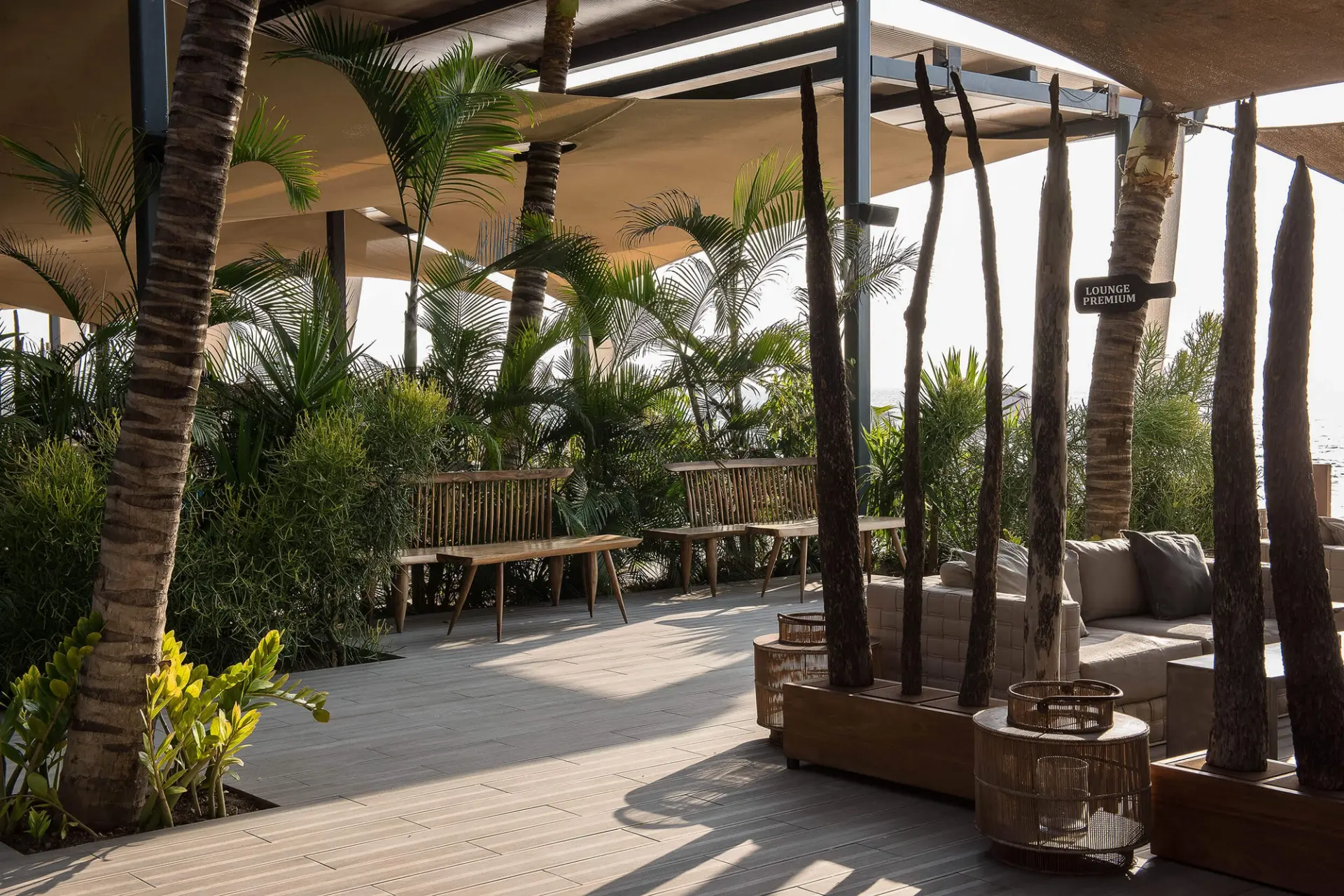 Lounge com velas de sombreamento, deck de madeira, palmeiras e vista mar — design de interiores de restaurante de luxo Luanda, Angola