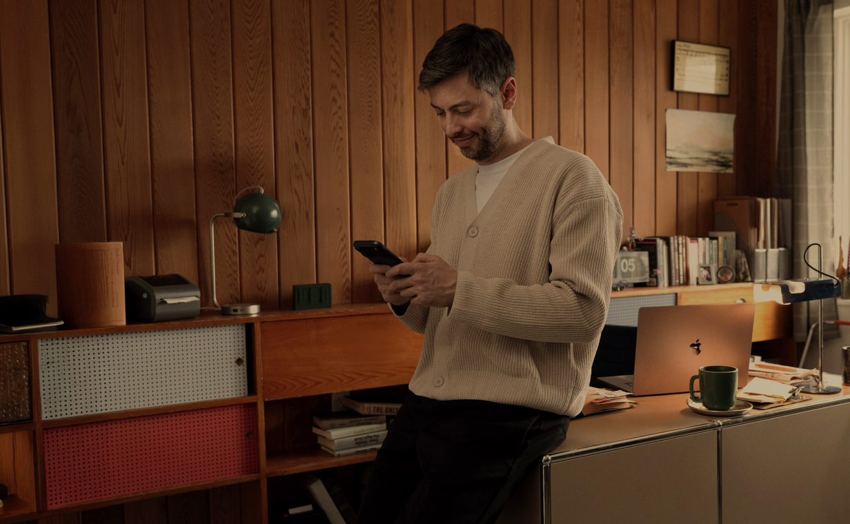 A man in his home office works from his phone