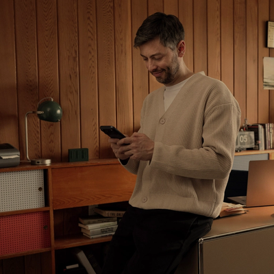 A man in his home office works from his phone
