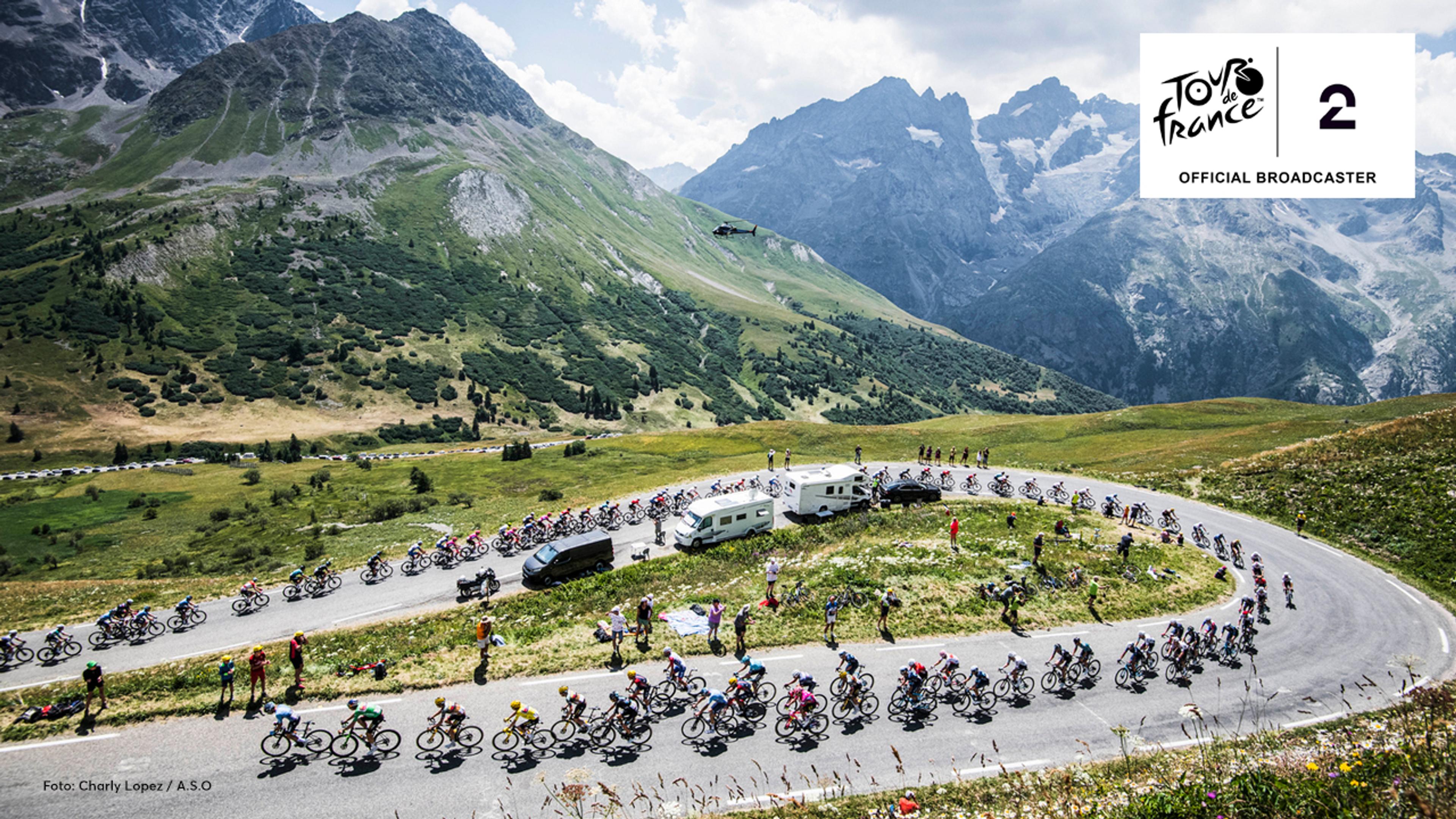 Syklister i rittet Tour de France på fransk landevei med flott landskap i bakgrunnen.