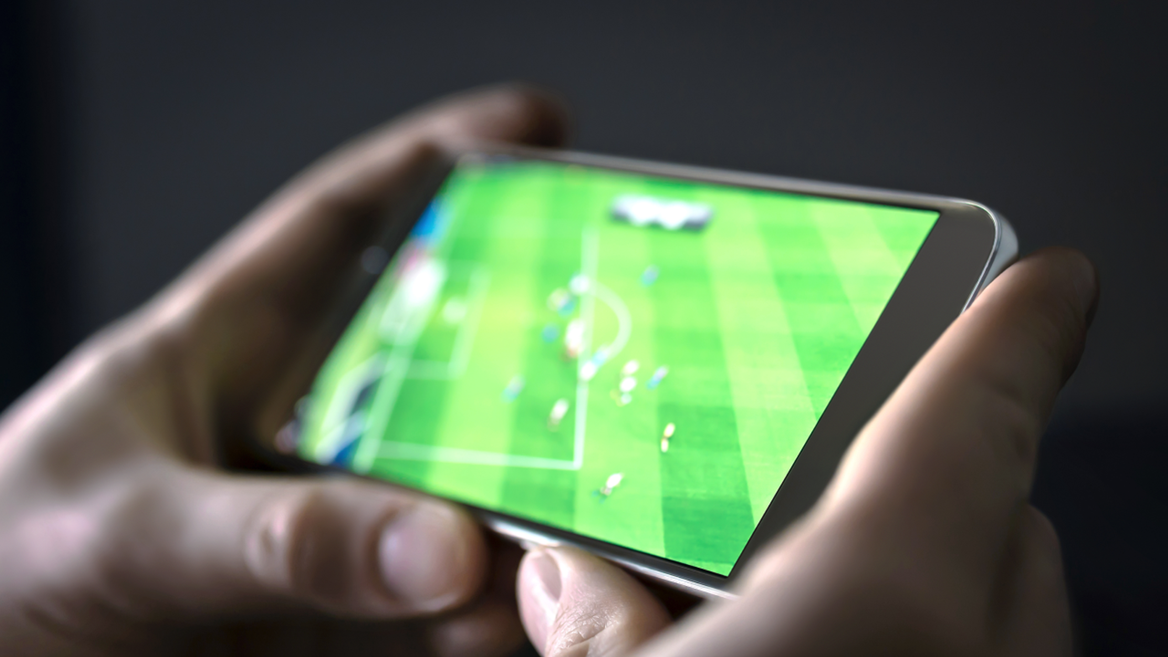 En person ser på fotballkamp på en mobilskjerm