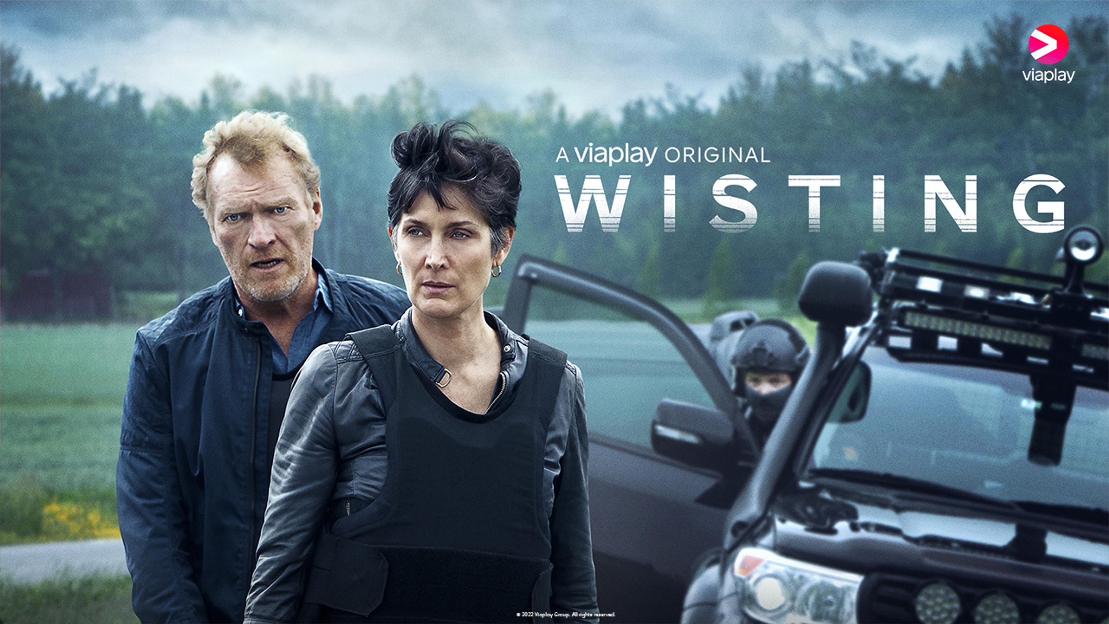 Hovedpersonene Sven Nordin og Carrie-Anne Moss står i skuddsikre vester foran en bil