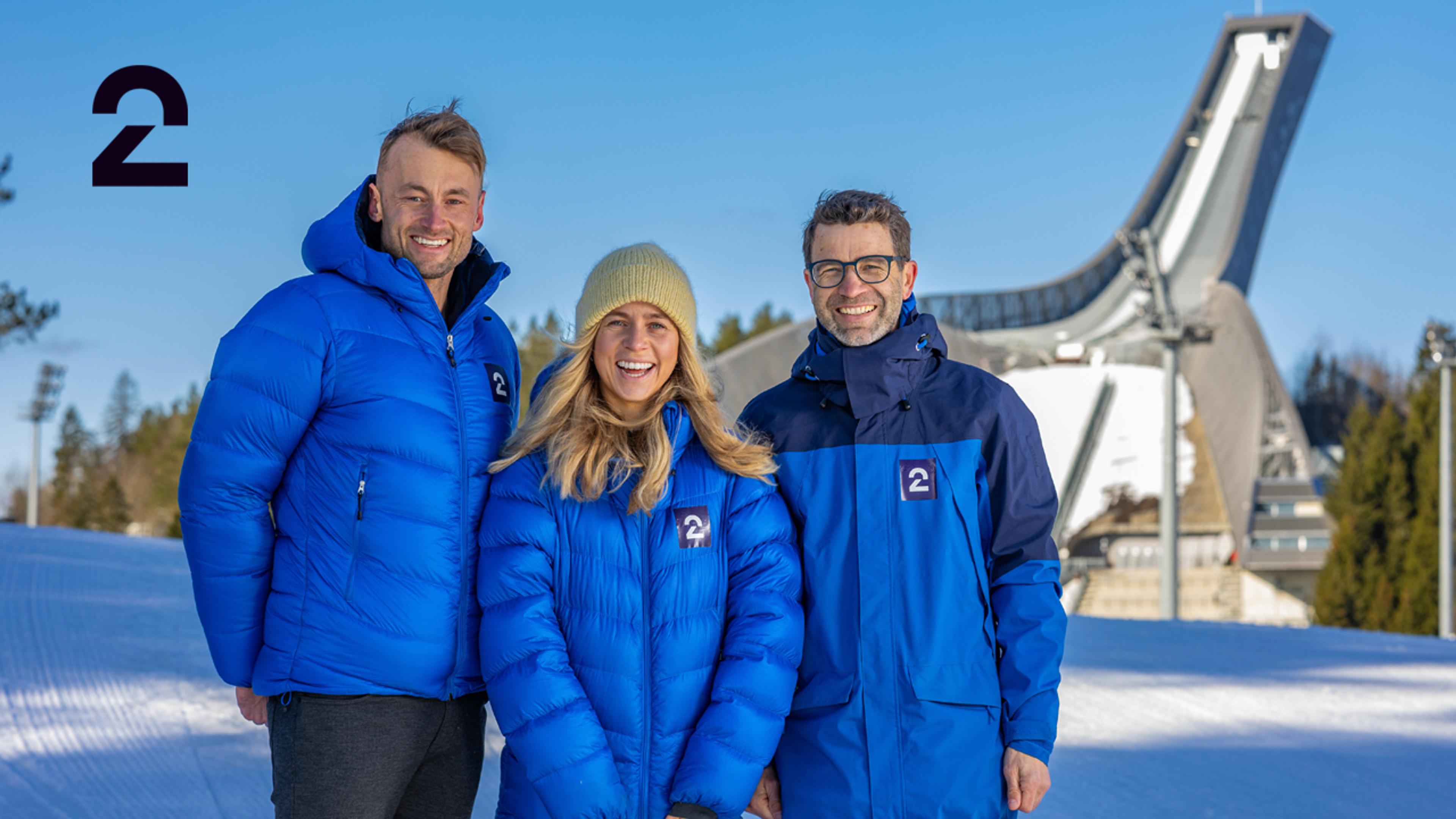 Bilde av programlederne i TV 2s vinterstudio: Petter Northug, Tiril Eckhoff og Ole Einar Bjørndalen som står i vinterlandskap foran Holmenkollen.