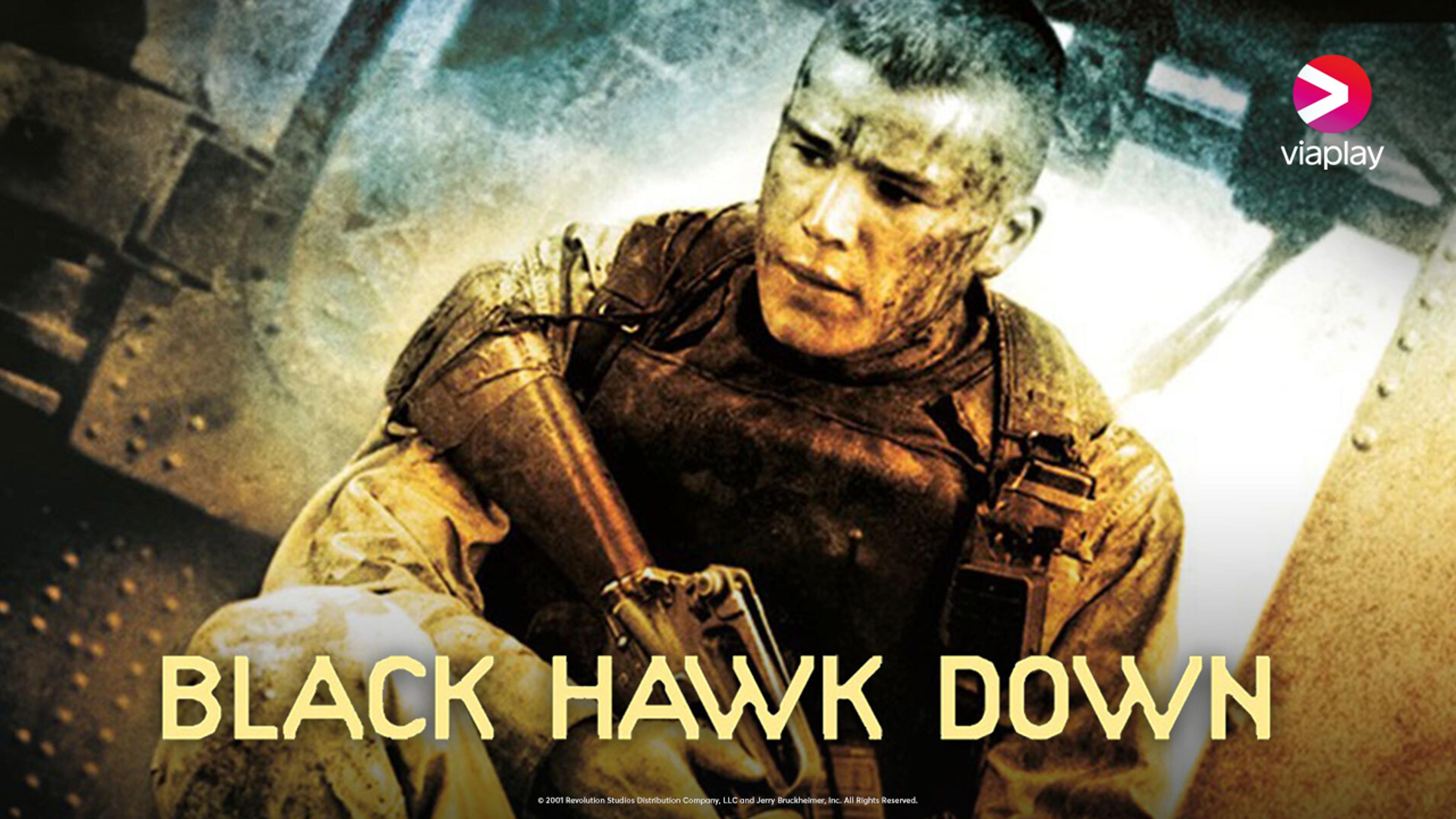 Trist soldat i full uniform sitter foran et helikopter med våpen i hånd.