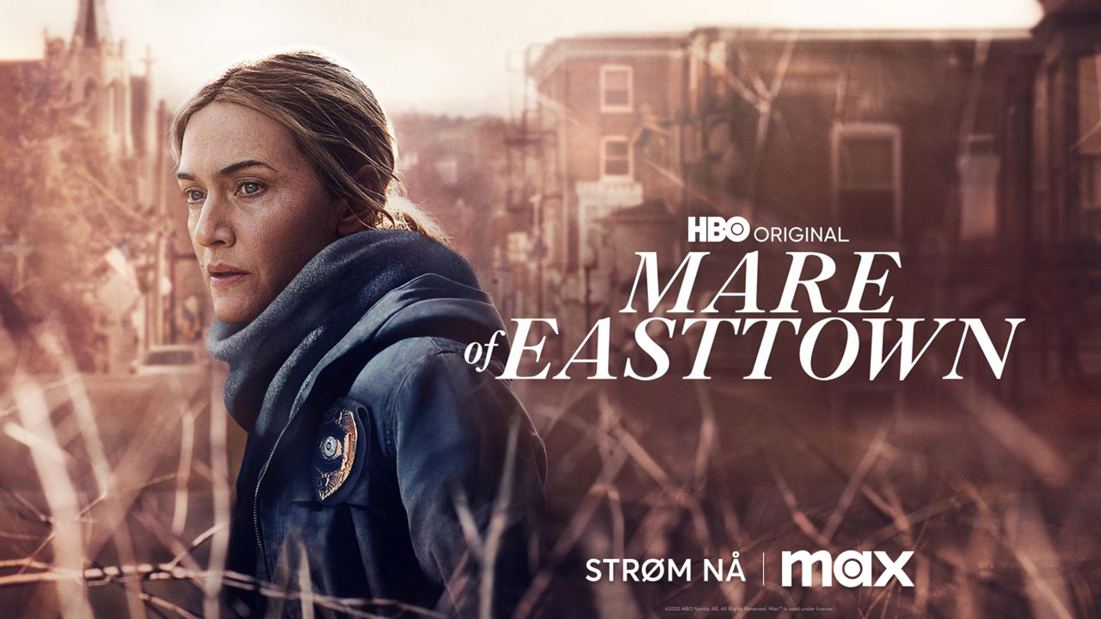 Kate Winslet i Mare of Easttown står foran en gate i en liten by i USA.
