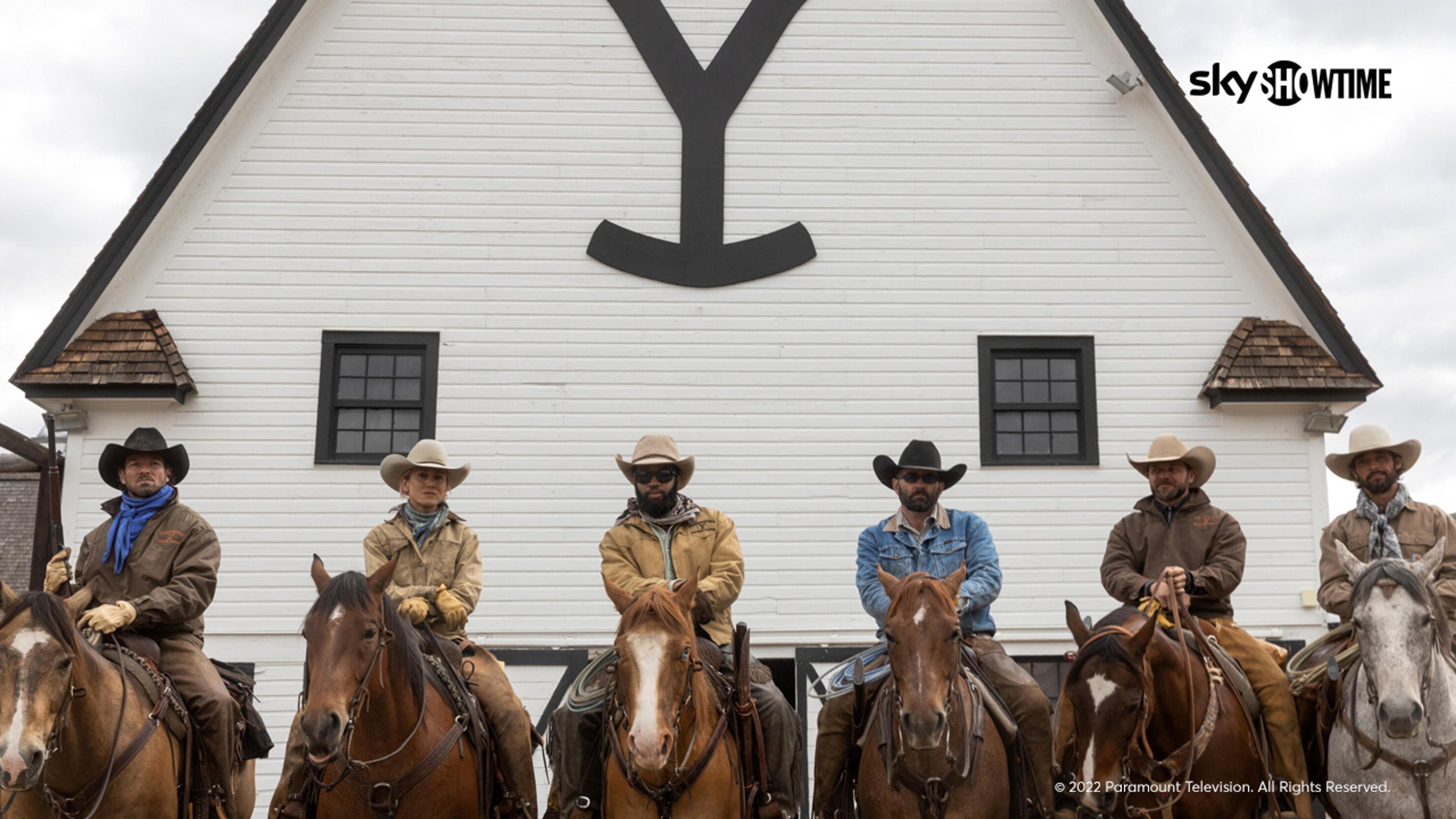Cowboyene på Yellowstone Farm sitter på hestene sine foran låven.
