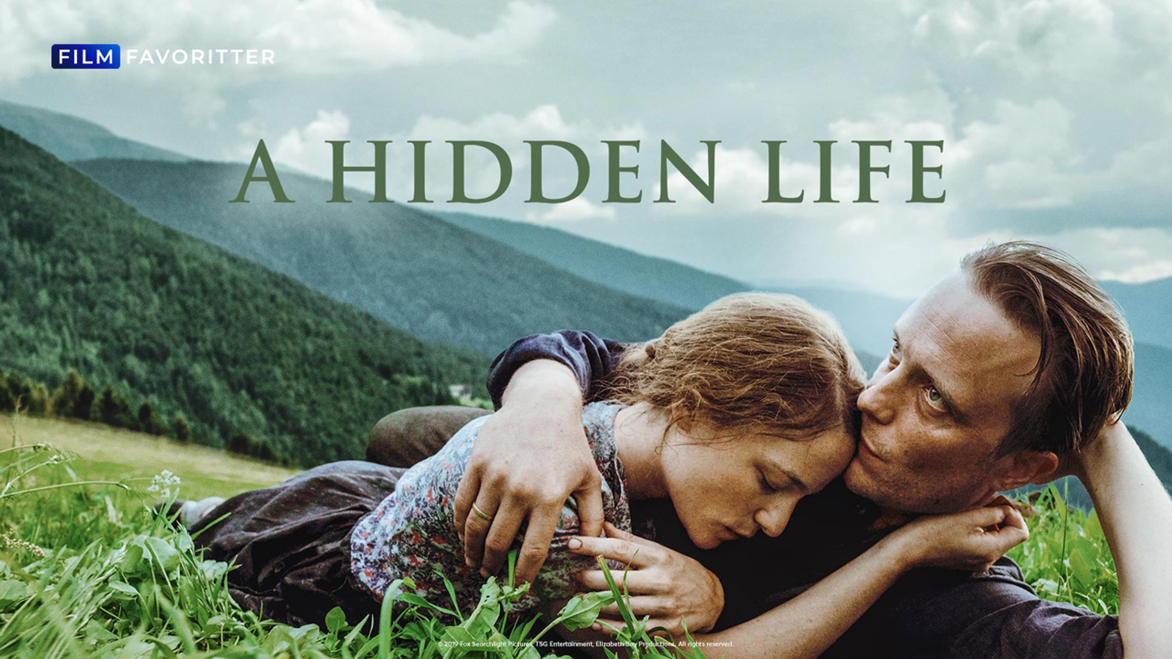 En kvinne og en mann ligger i armene til hverandre på en eng med fjell i bakgrunnen.