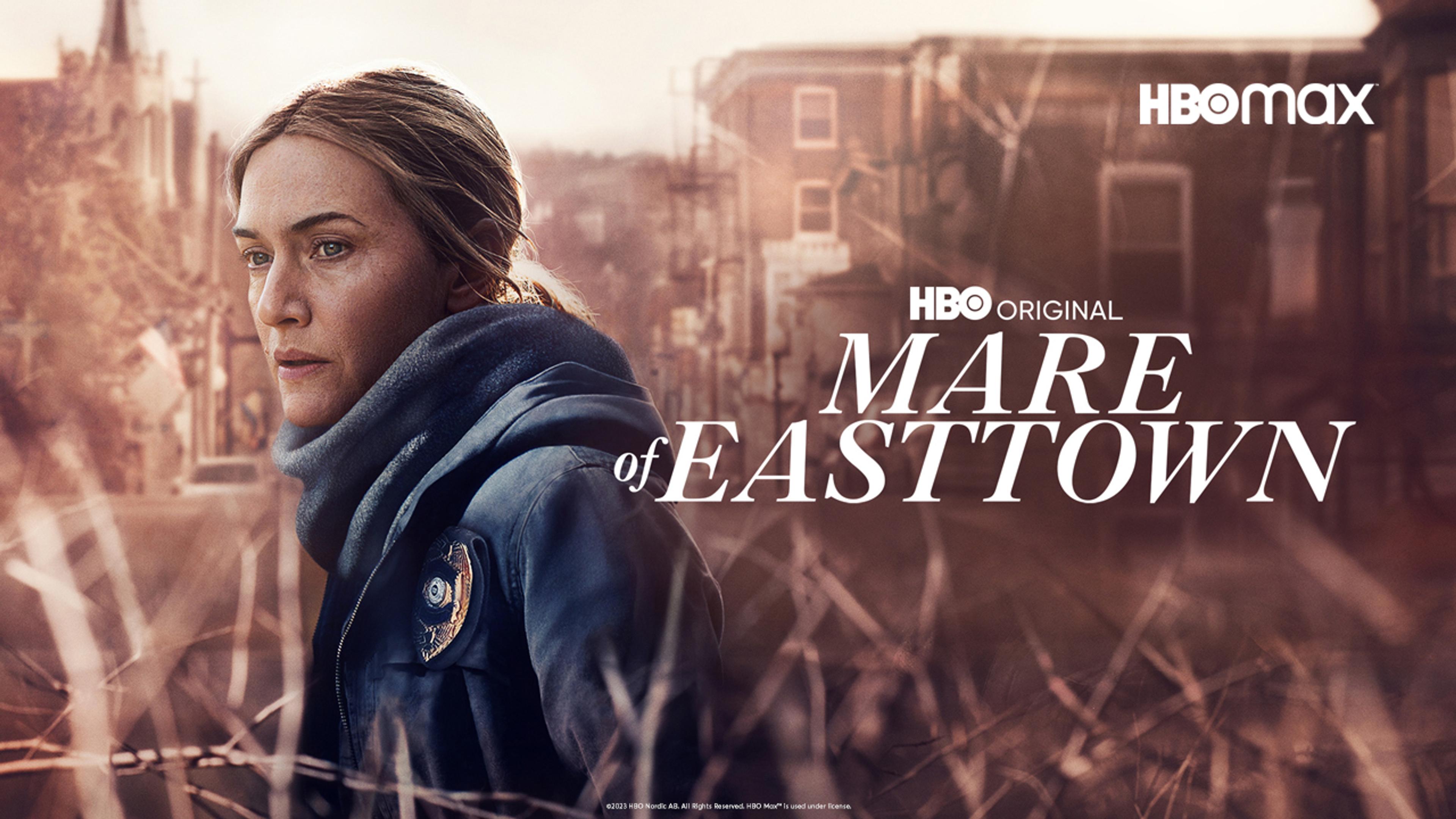 Kate Winslet i Mare of Easttown står foran en gate i en liten by i USA.