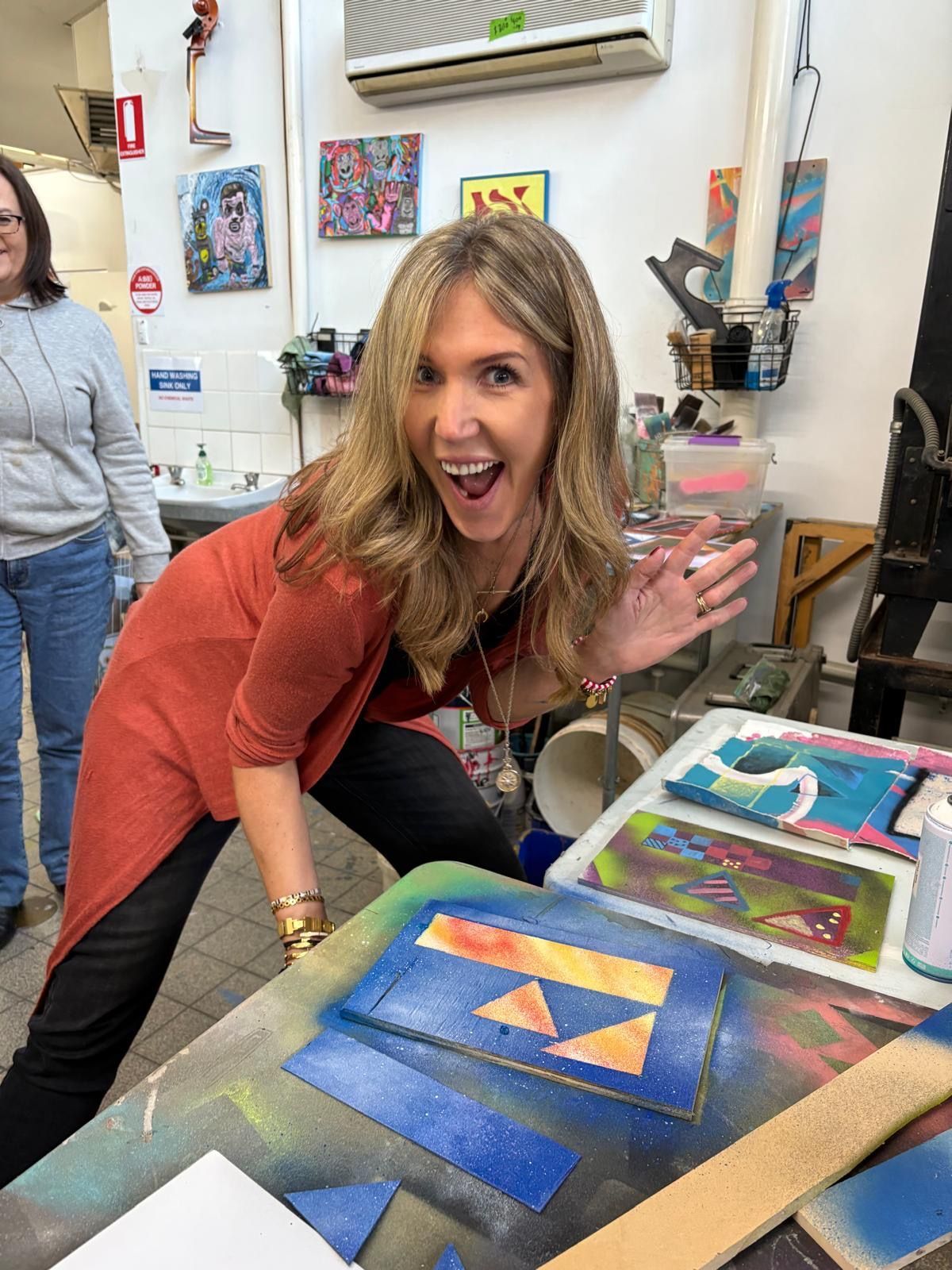 Kylie standing over her creative painting of the Fuller 'F'