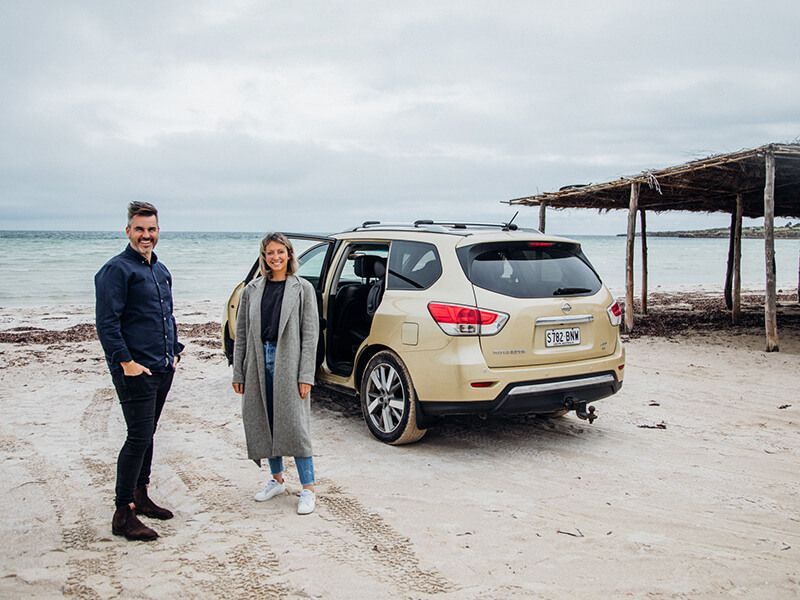 Fuller team at a beach standing in front of a car