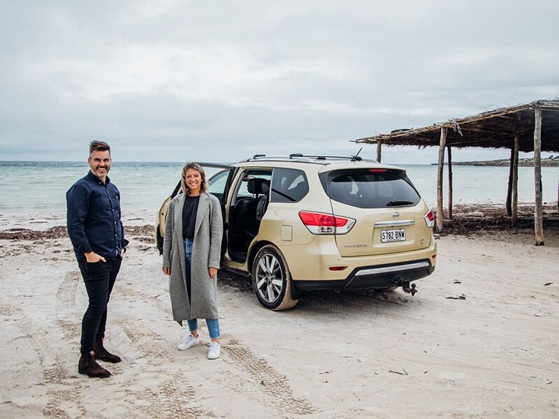 Fuller team at a beach standing in front of a car