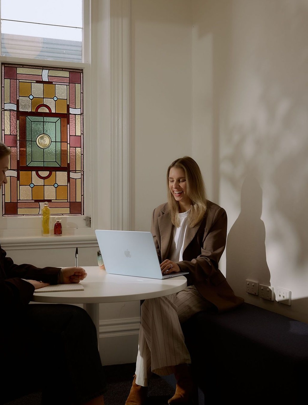 Rachael and Nadia sitting around a table with a stained glass window in the background
